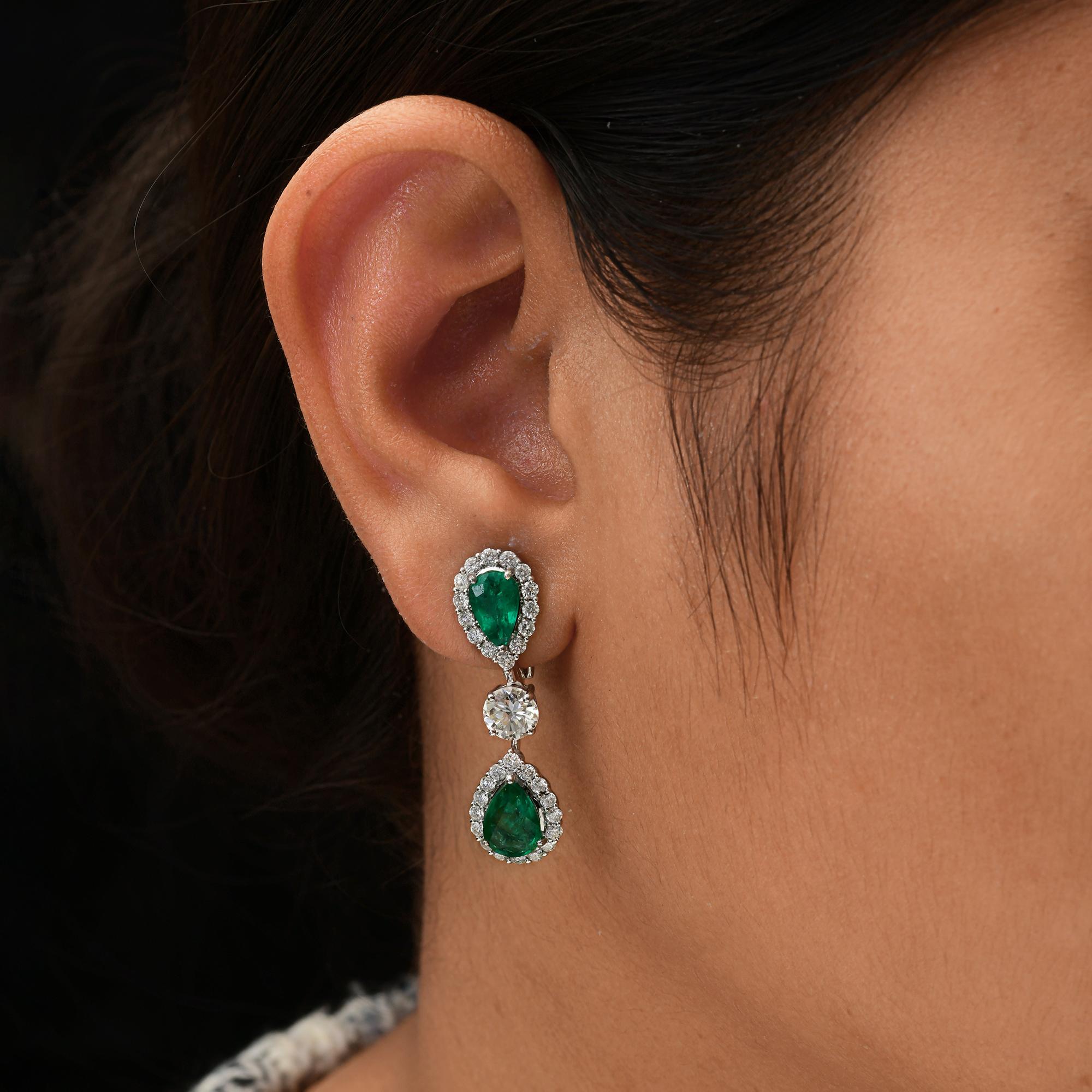 Teardrop 18K White Gold 6.66Tcw Zambian Emerald Halo Diamond Dangle Earrings.
Diese exquisiten Ohrringe sind mit zwei lebhaften, birnenförmigen, natürlichen Smaragden besetzt - einer oben und einer unten - und werden von einem Kranz funkelnder