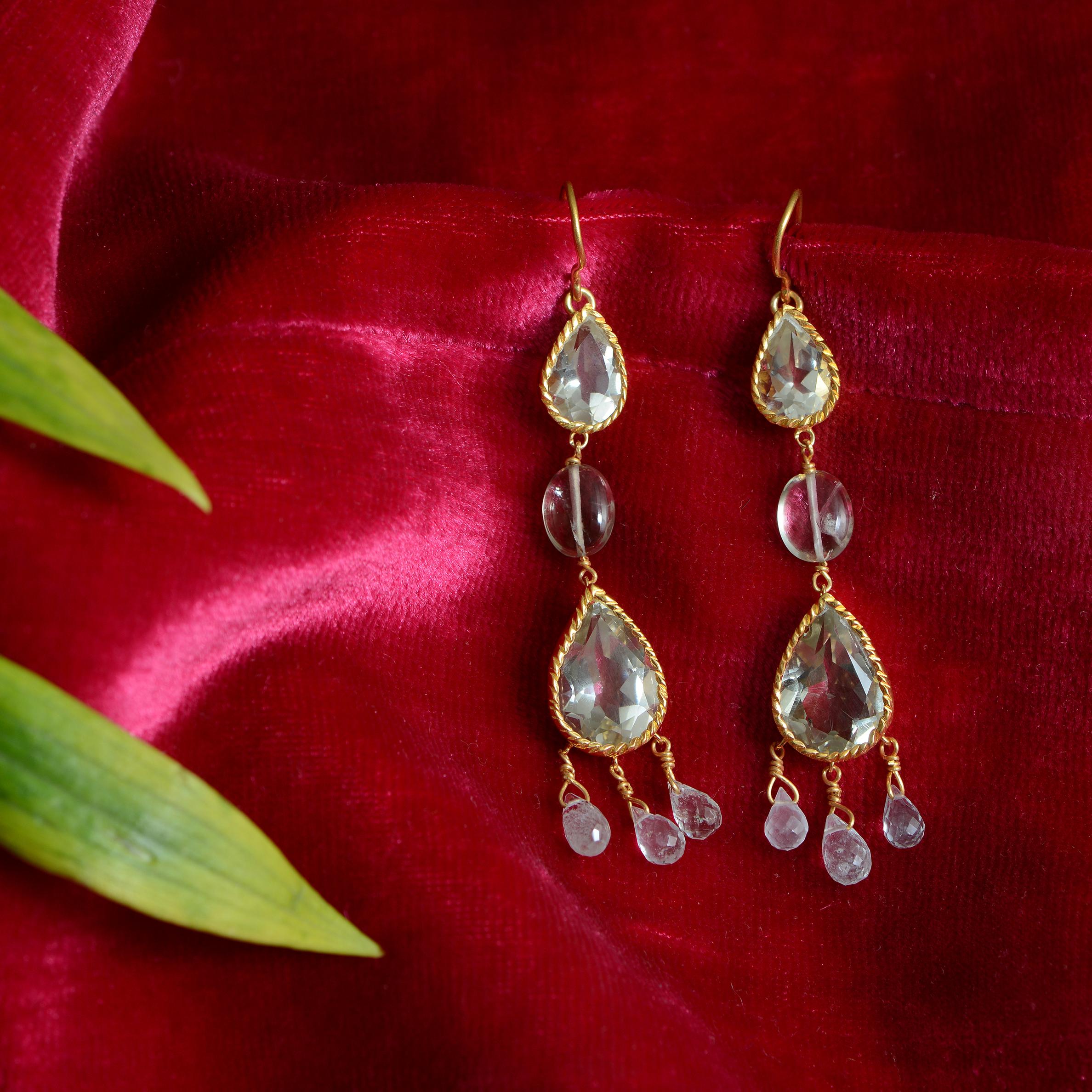These beautiful teardrop shaped green amethyst dangle earrings have been handmade in our workshops and have a central aquamarine and aquamarine drops.
They are made in sterling silver coated with 24kt gold plate and are limited edition.
The earrings
