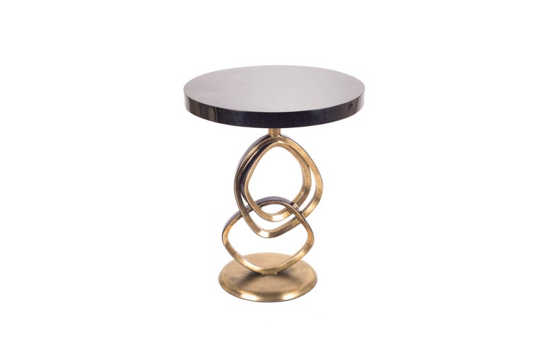 The Teardrop II side table is an elegant design with exquisite detailing. The sculptural rings are inlaid in a mixture of black pen shell bronze-patina brass and the top is in black pen shell. This piece is designed by the daughter of Ria and Yiouri
