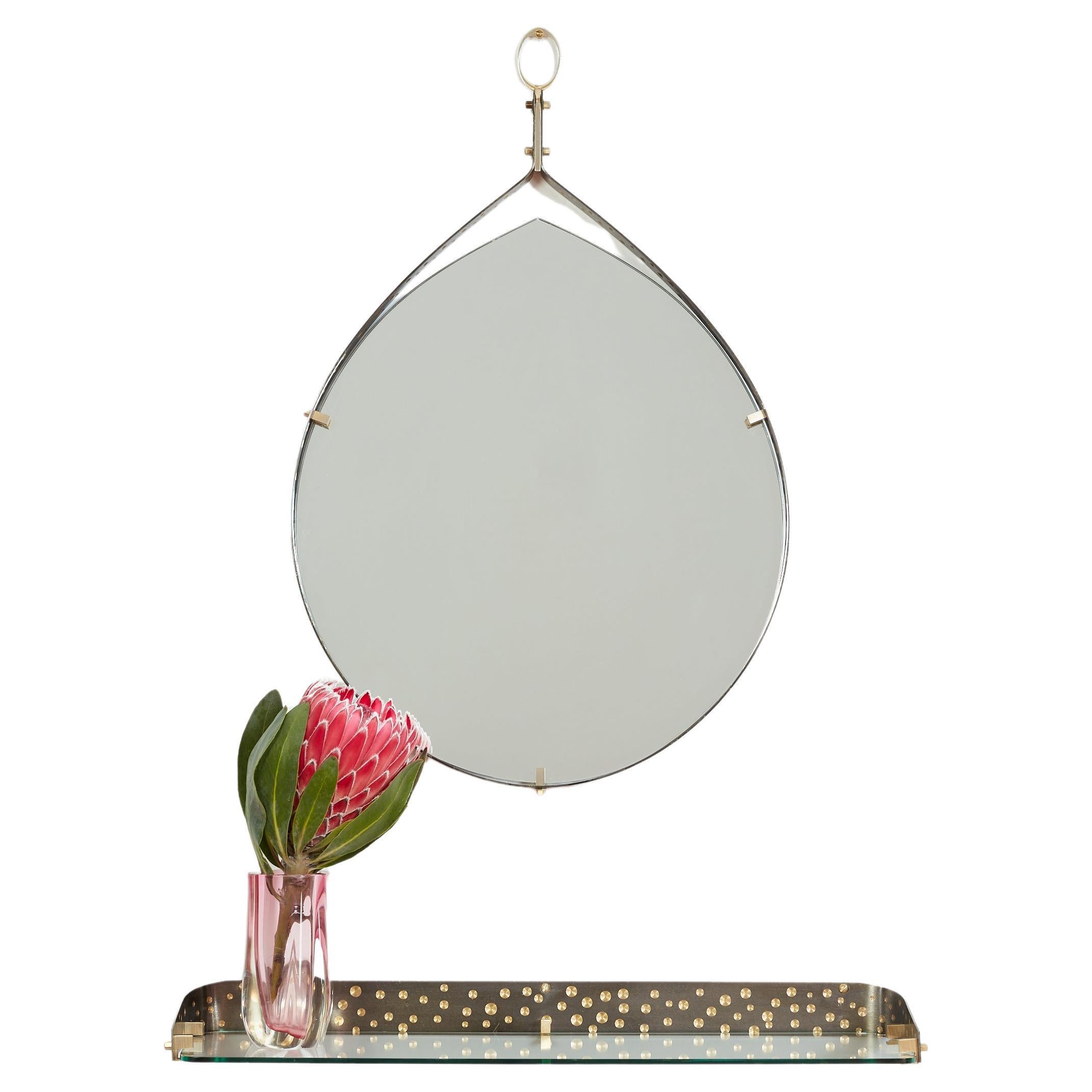 Miroir italien des années 1950 en fer argenté et laiton, de forme larmoyante, avec des détails en laiton perforé sur le bord.  
Conçu par Ambrogio  & De Berti - Italie, années 1950 - ce miroir est doté d'une console en verre flottante assortie.
