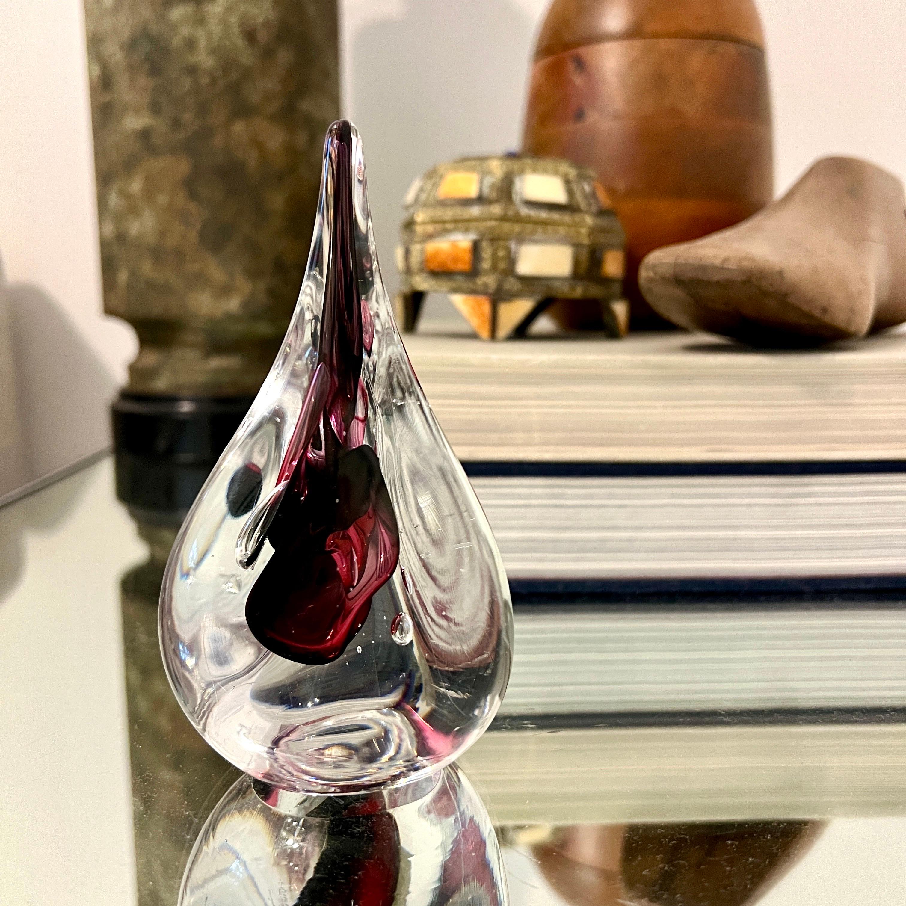 Fermacarte scultoreo a tre lati della metà del secolo scorso, a forma di goccia stilizzata   Il vetro di Murano con la tecnica del Sommerso presenta un centro color ametista racchiuso in vetro trasparente con accenti di bolle controllate.  È un