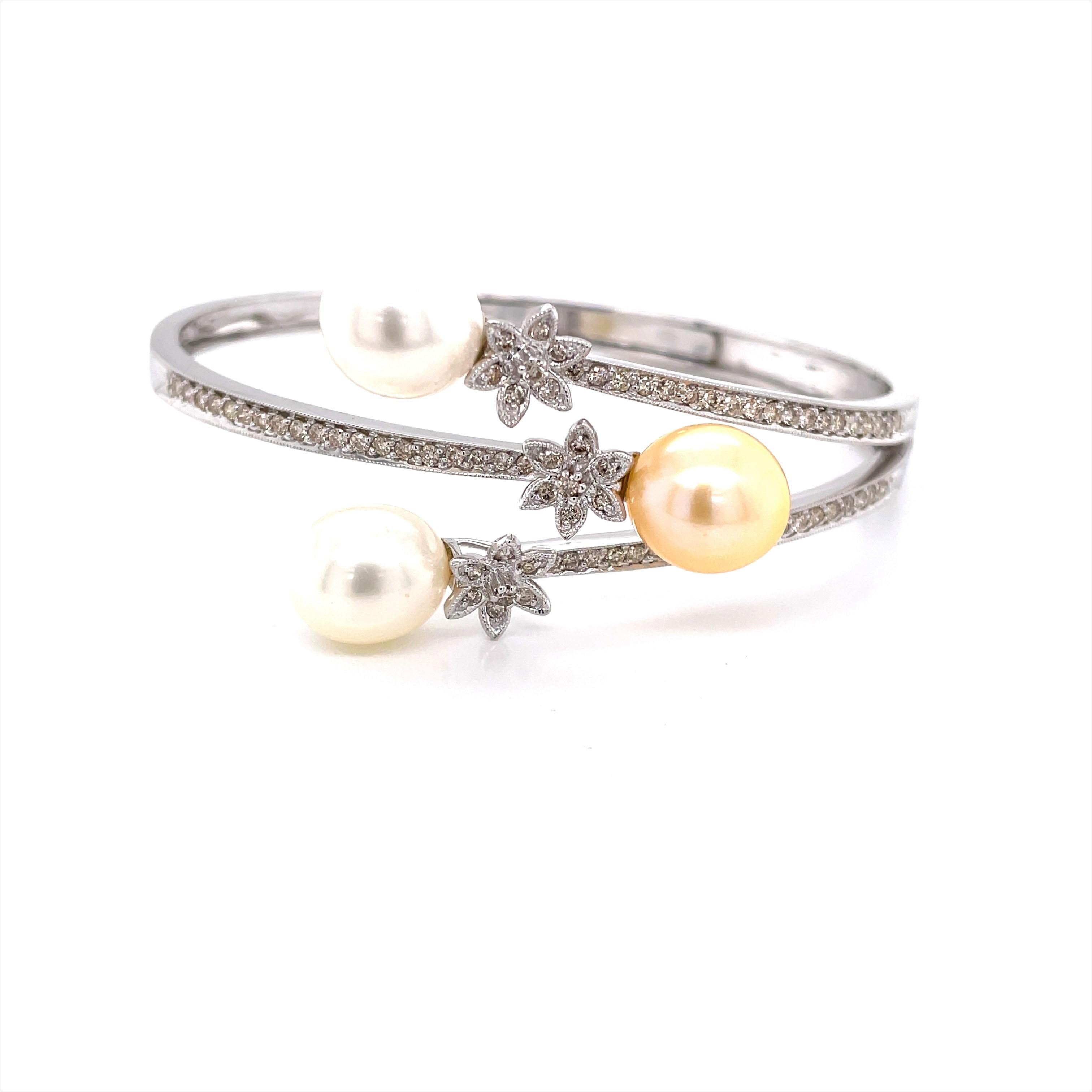 A dressy bangle bracelet, perfect for bridal or special occasion. Three 9.7mm tear drop shaped AAA cultured Akoya pearls, two white and one champagne, are featured on the three prong wrap design of this eighteen karat 18 karat white gold 2.5 inch