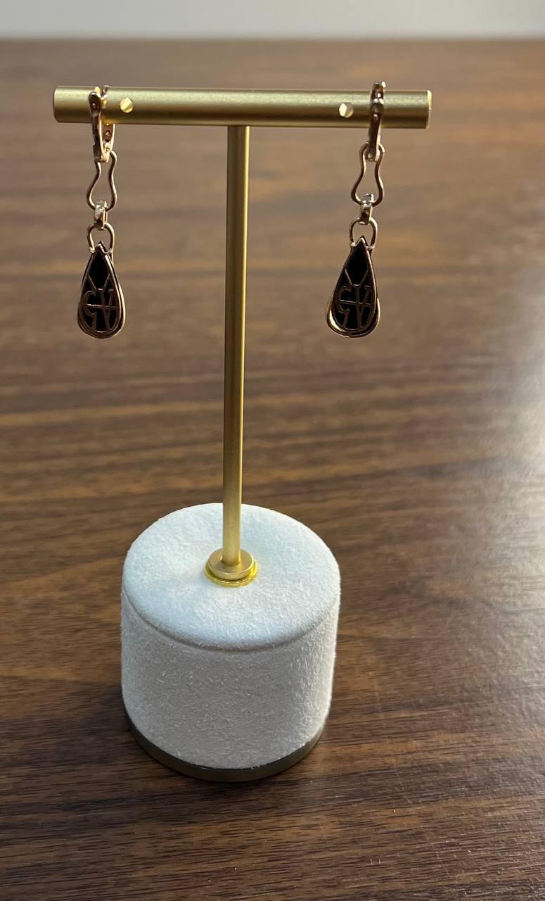 Ein raffiniertes Paar tropfenförmiger Ohrringe mit einem tropfenförmigen Design und verschlungenen schwarzen Onyxen. Die Ohrringe hängen an einer zarten Gliederkette aus warmem 14-karätigem Gelbgold. Das Design ist sowohl elegant als auch modern,