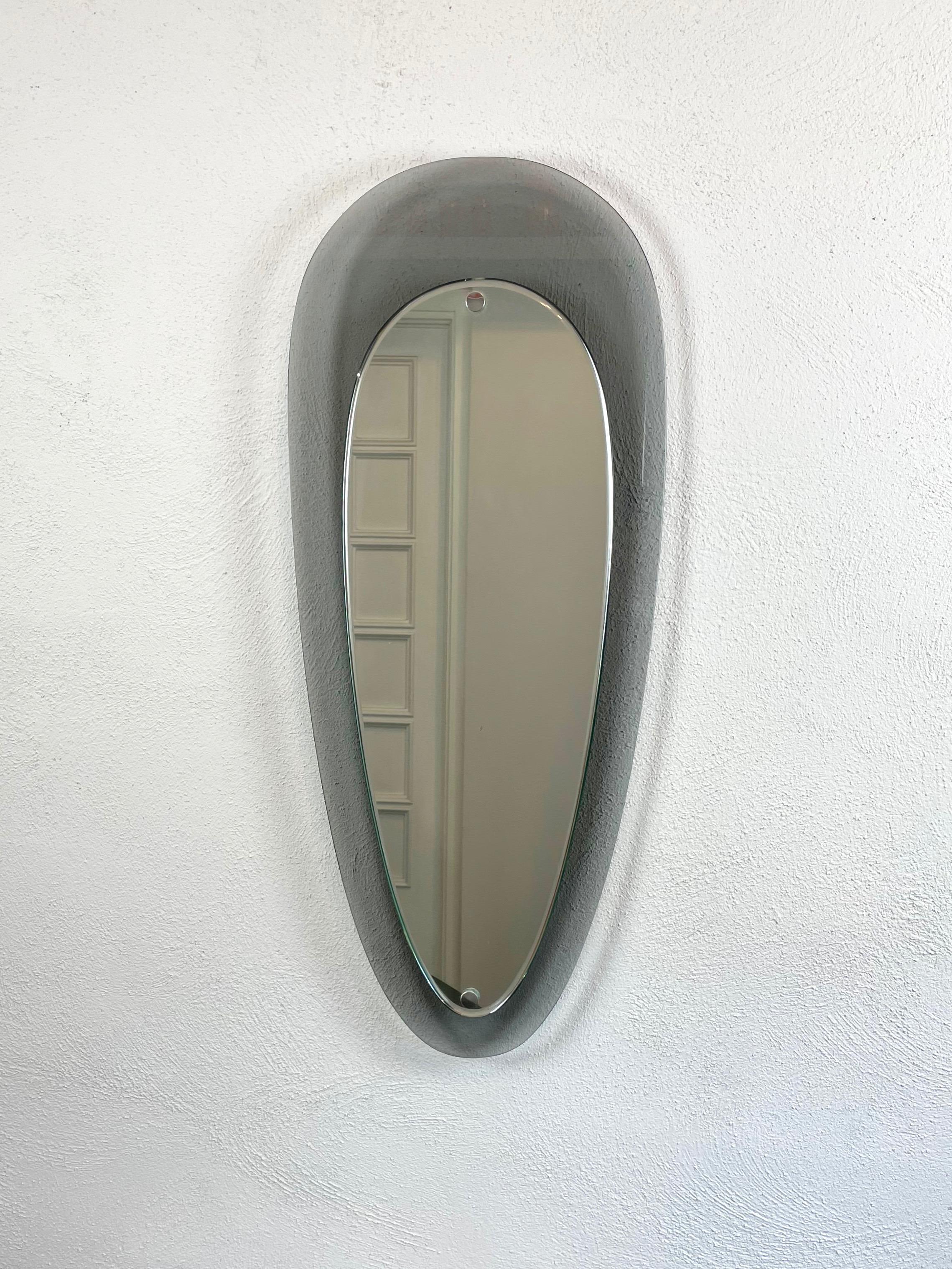 Teardrop-shape wall mirror featuring a grey glass frame in the style of Fontana Arte. Made in Italy in the 1970s.