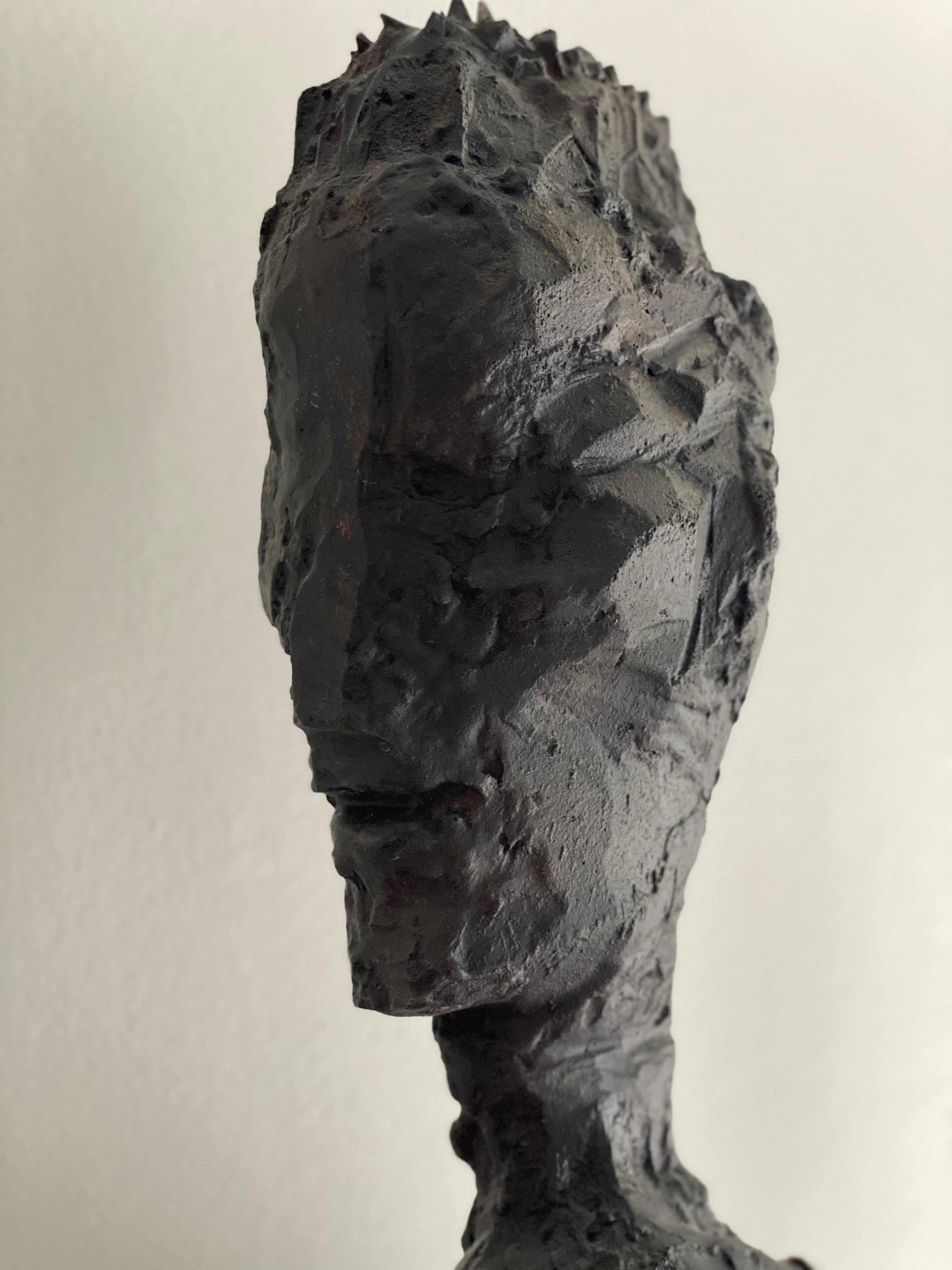 Une sculpture en bronze de John Brevard représente un homme dans un profond état de contemplation, debout comme en prière. Son attention est entièrement tournée vers le téléphone portable qu'il tient devant lui, symbolisant l'attachement du monde