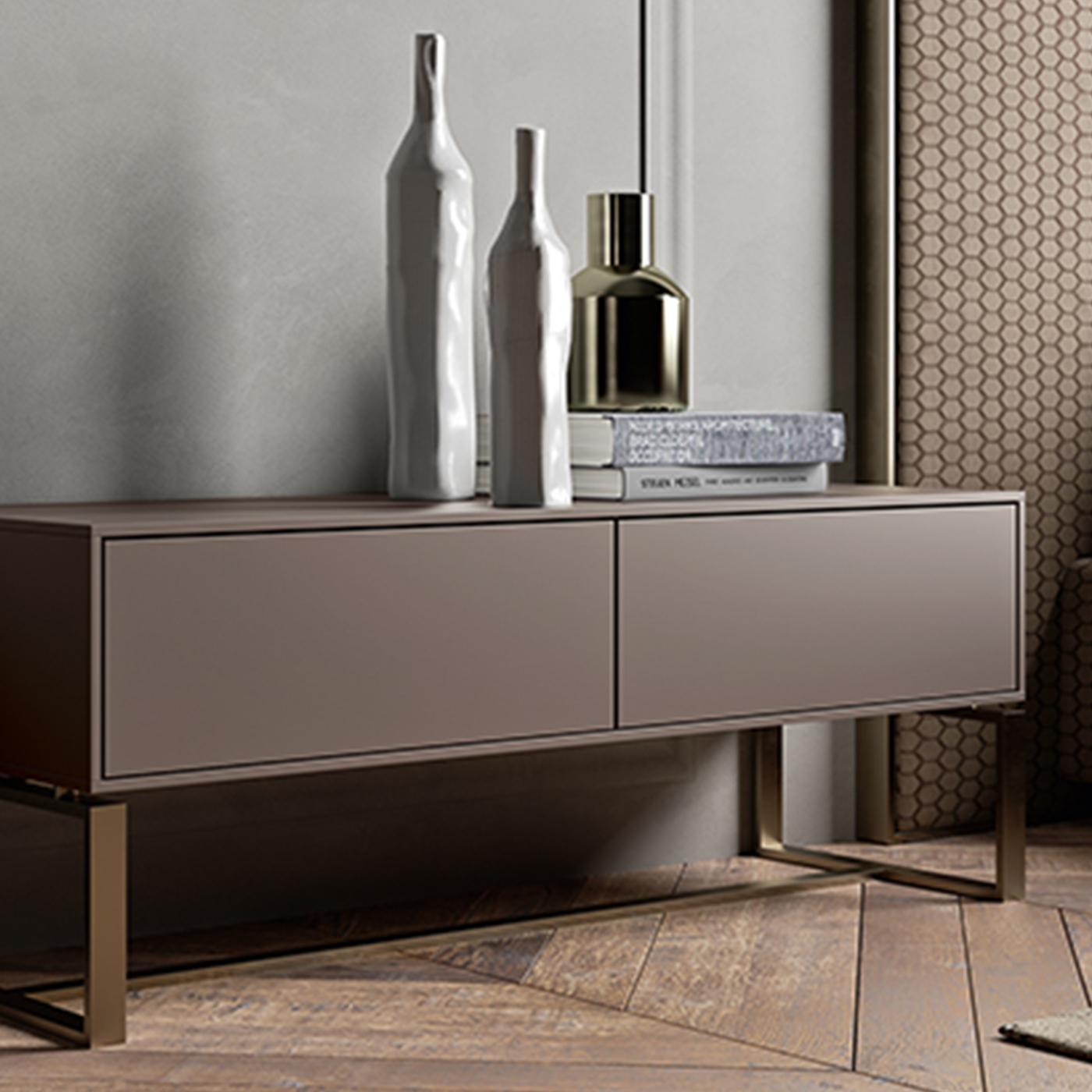 A stunning example of modern style, this refined nightstand features an elongated, sophisticated silhouette. The MDF frame lacquered in matte gray stands on a streamlined base in brass-finished steel comprised of rectangular profiles connected