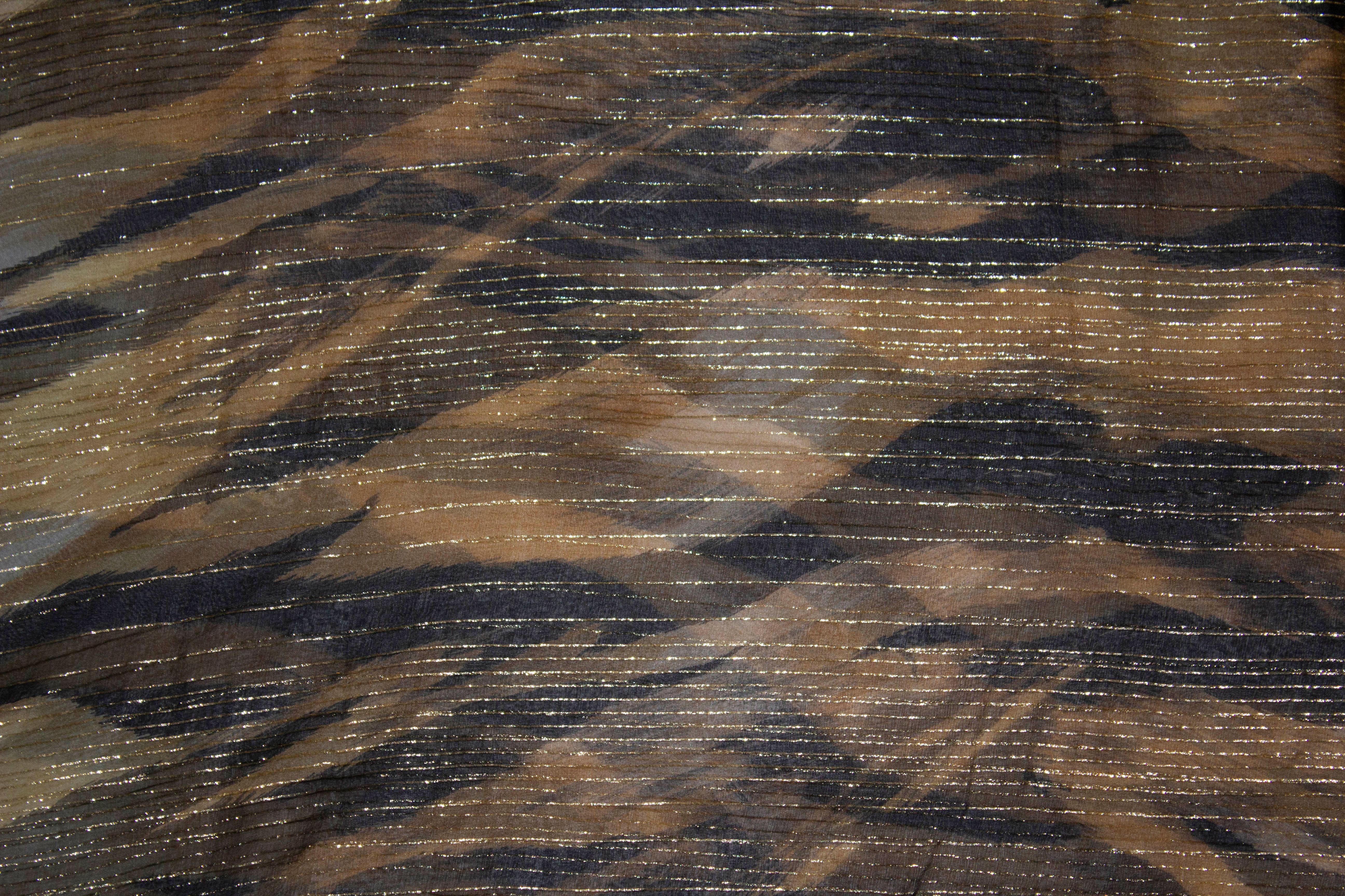 A wonderful silk chiffon scarf by Ted Lapidus Paris. In a mixture of black and gold the scarf measures 66'' x 70''