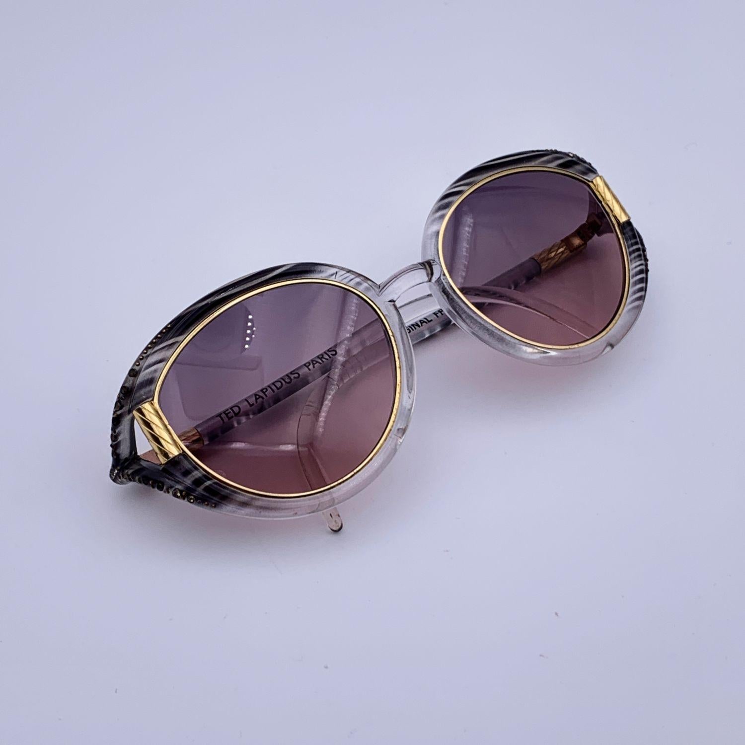 Vintage oval B10 sunglasses from the 70s by TED LAPIDUS. Grey striped and clear frame accented with gold metal elements. Gradient light grey and pink lenses (100% UV protection). Made in France

Details

MATERIAL: Plastic

COLOR: Grey

MODEL: