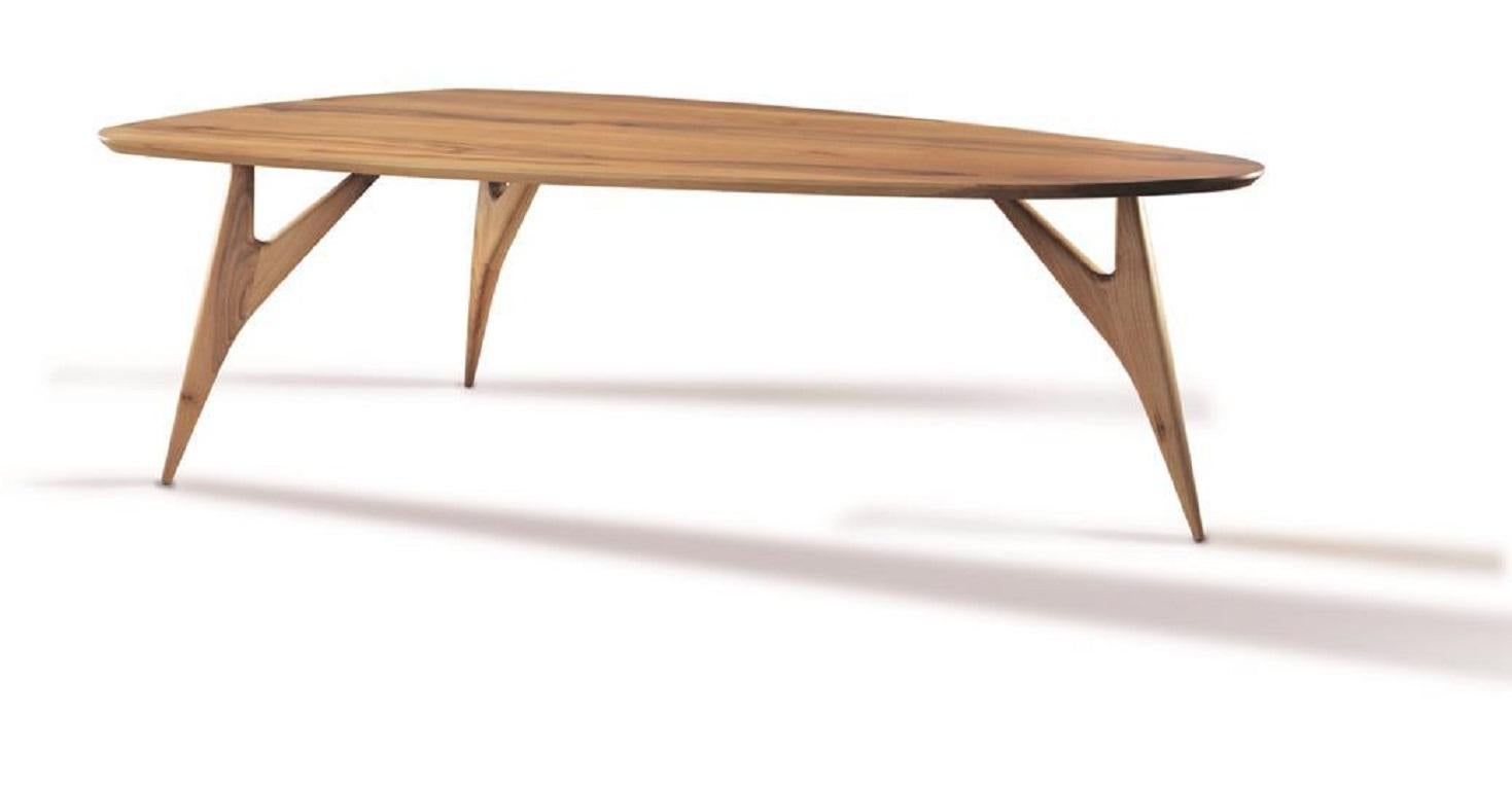 The modern flair of aerodynamic lines meets the natural strength and warmth of a solid walnut structure in this elegant dining table. The tapered and branched design of the three supporting legs is minutely shaped by hand, creating a sculptural base