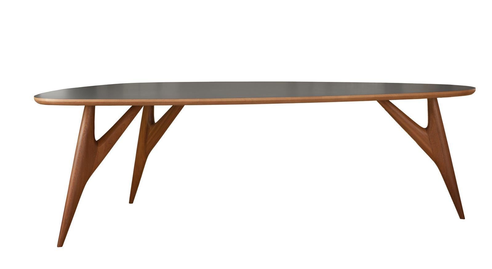 This remarkable wooden dining table is distinguished by an aerodynamic silhouette capable of infusing character into any modern dining area. The sail-shaped, gray-lacquered top rests on three tapered legs displaying a stylized branched design that