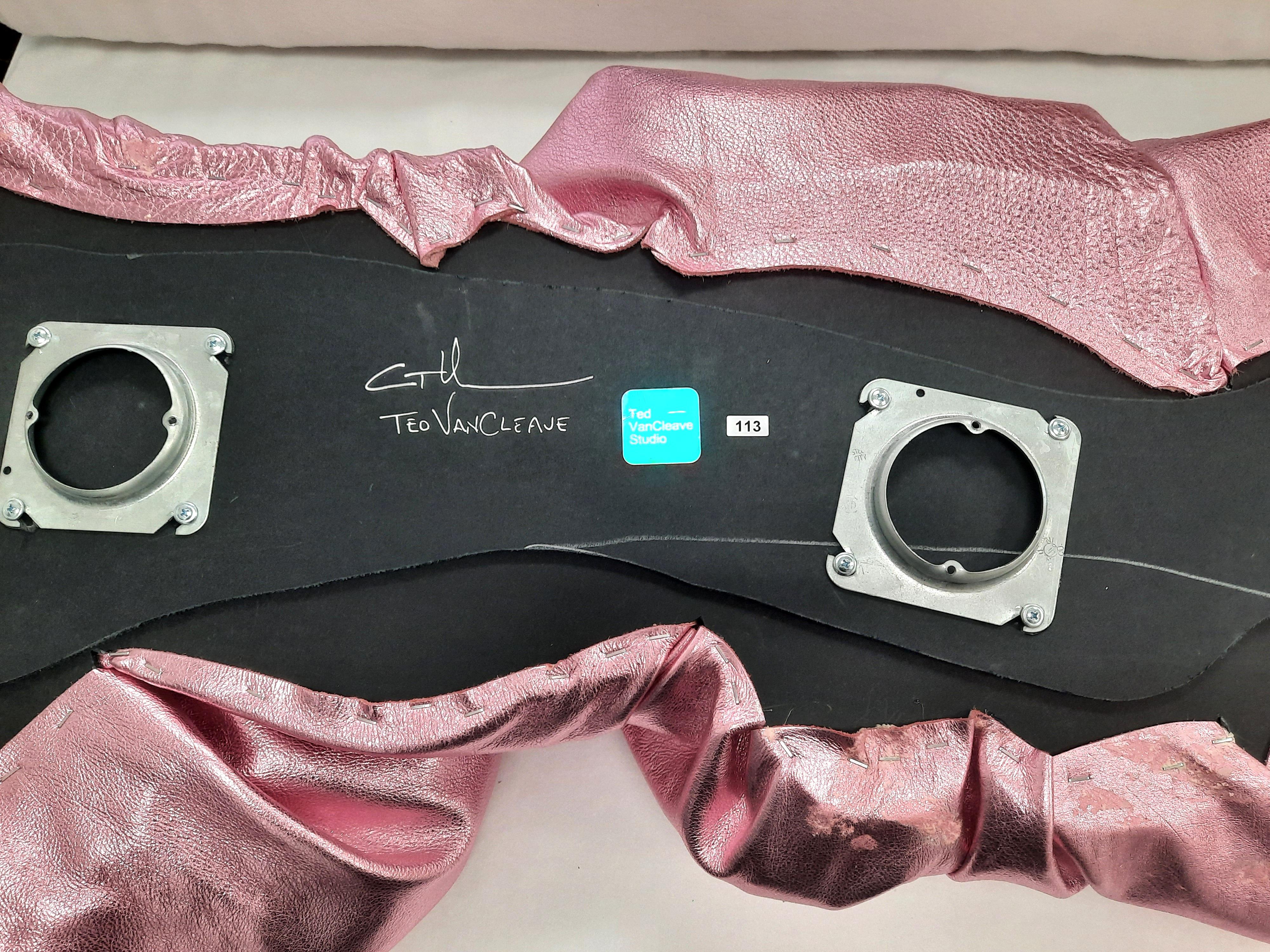 This light-pink wall sculpture by Ted VanCleave transforms a single sheet of metallic leather into a sinuous, process-driven study of material and form. Its creased, crinkled, and softly wrinkled surface catches the light like a rose-toned pop