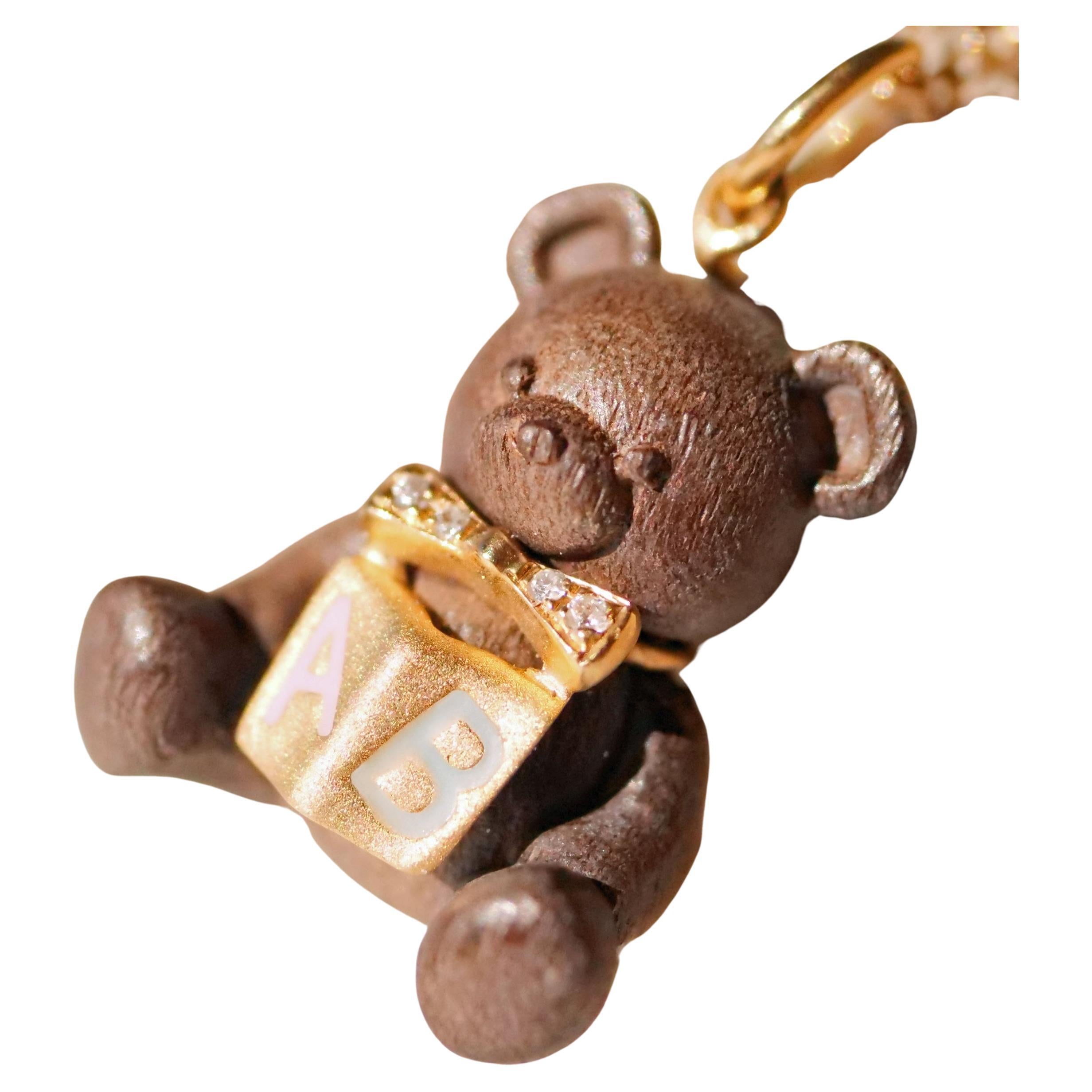 a high quality, detailed goldsmith work set with 4 full cut diamonds total approx. 0.01 ct, W / SI1-2, the cute teddy bear is made of precious wood and solid gold in 18 carat, with book (enamel letters A B in pink and blue) and bow applique in front