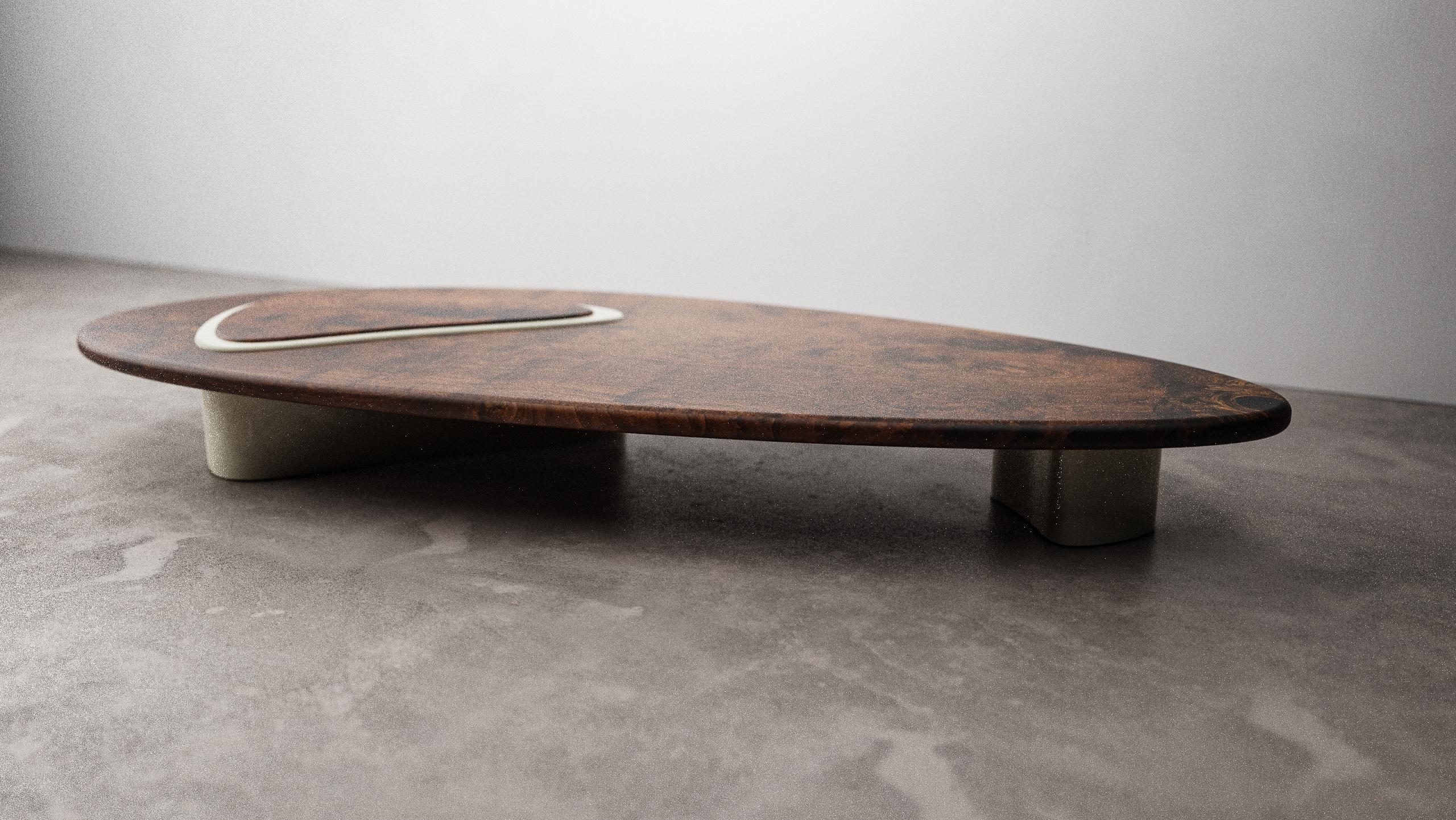 La table basse Tehama de Christophe Mark est une pièce unique fabriquée à la main. Le plateau de la table est une plaque de noyer Claro massif dont la forme organique imite celle de la chrysomèle du noyer, le plus grand adversaire de l'arbre. Les