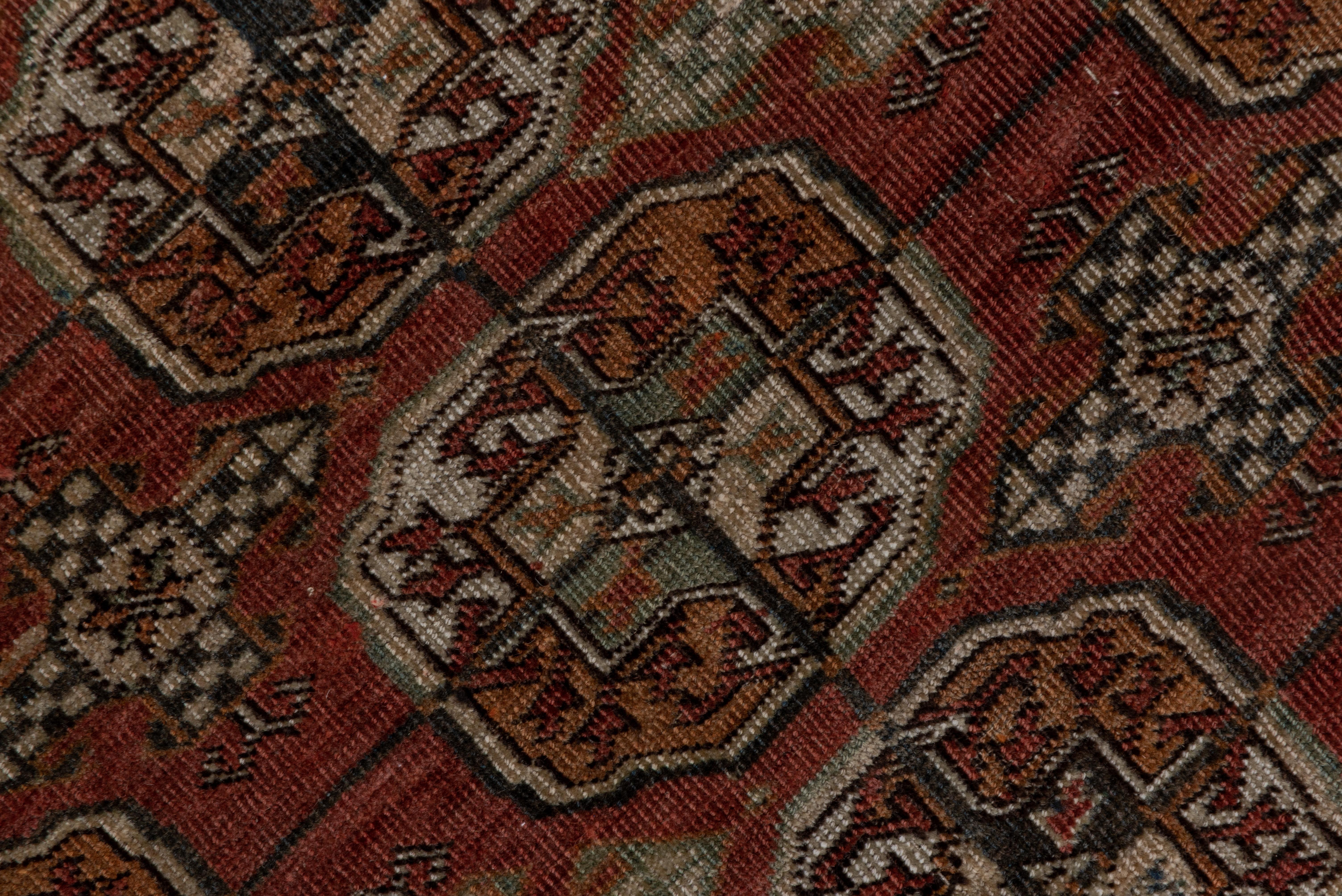 This Tekke Turkmen main carpet shows five columns of characteristic quartered guls on the red field with cruciform Kurbaghe minor guls between. The cross-centred border octagons are densely rayed. At each end is a broad panel with a rayed double