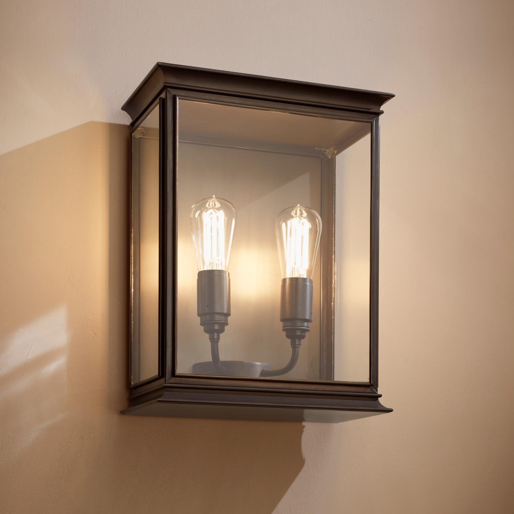 Wall light with decorative details on top and bottom in dark bronze, with outside fitted clear glass and spring closure. For indoor and outdoor use (IP44). Note that light bulb is not included.

Caret Squirrel Cage lamp 230V E27 2 x 7,7W 2300K. Main