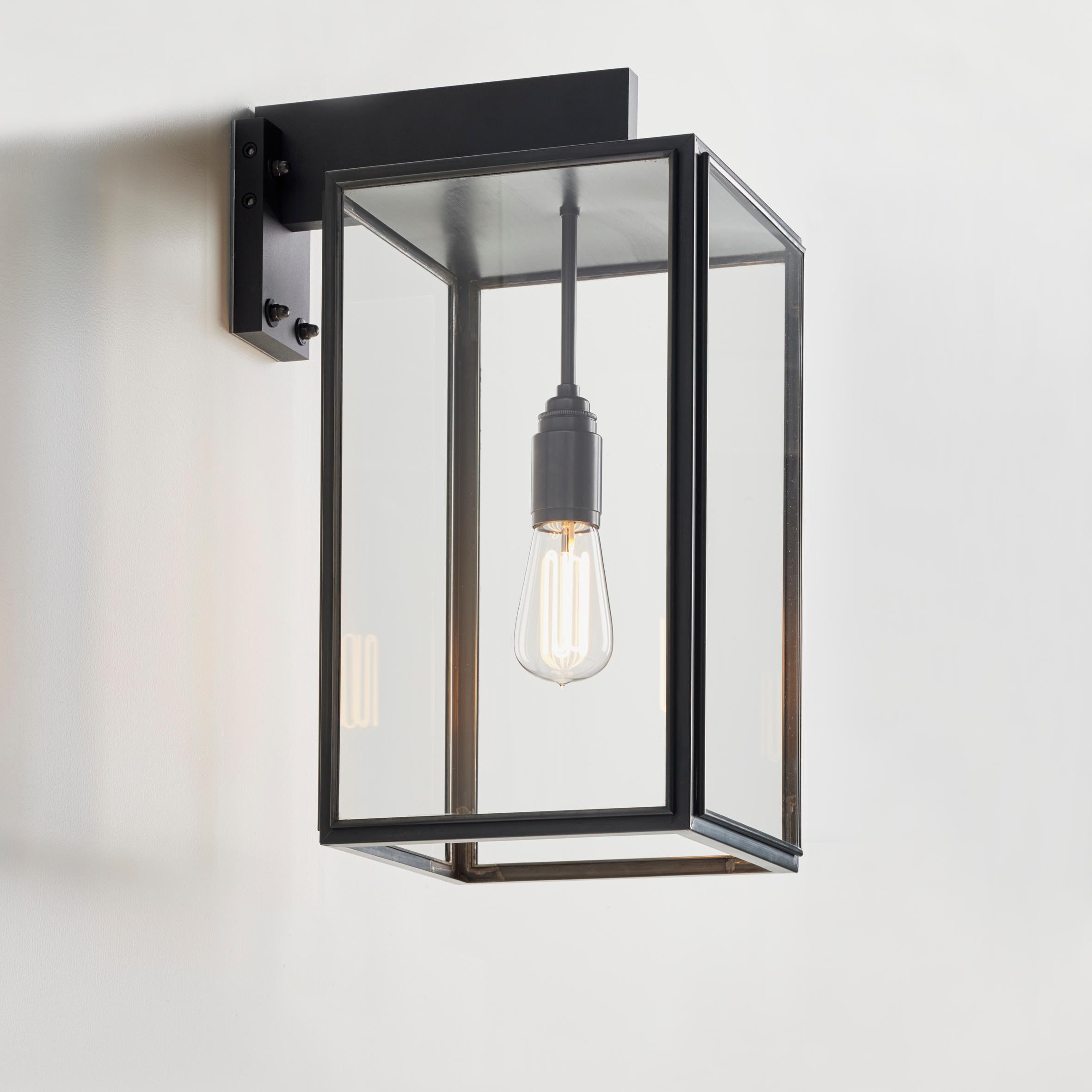 Eclectic wall light in dark bronze with outside fitted clear or frosted glass, closed top and open bottom. Wall bracket in bronze lacquered aluminium with forcible transit. For outdoor use (IP43).

Caret squirrel cage lamp 230V E27 7,7W 2300K.