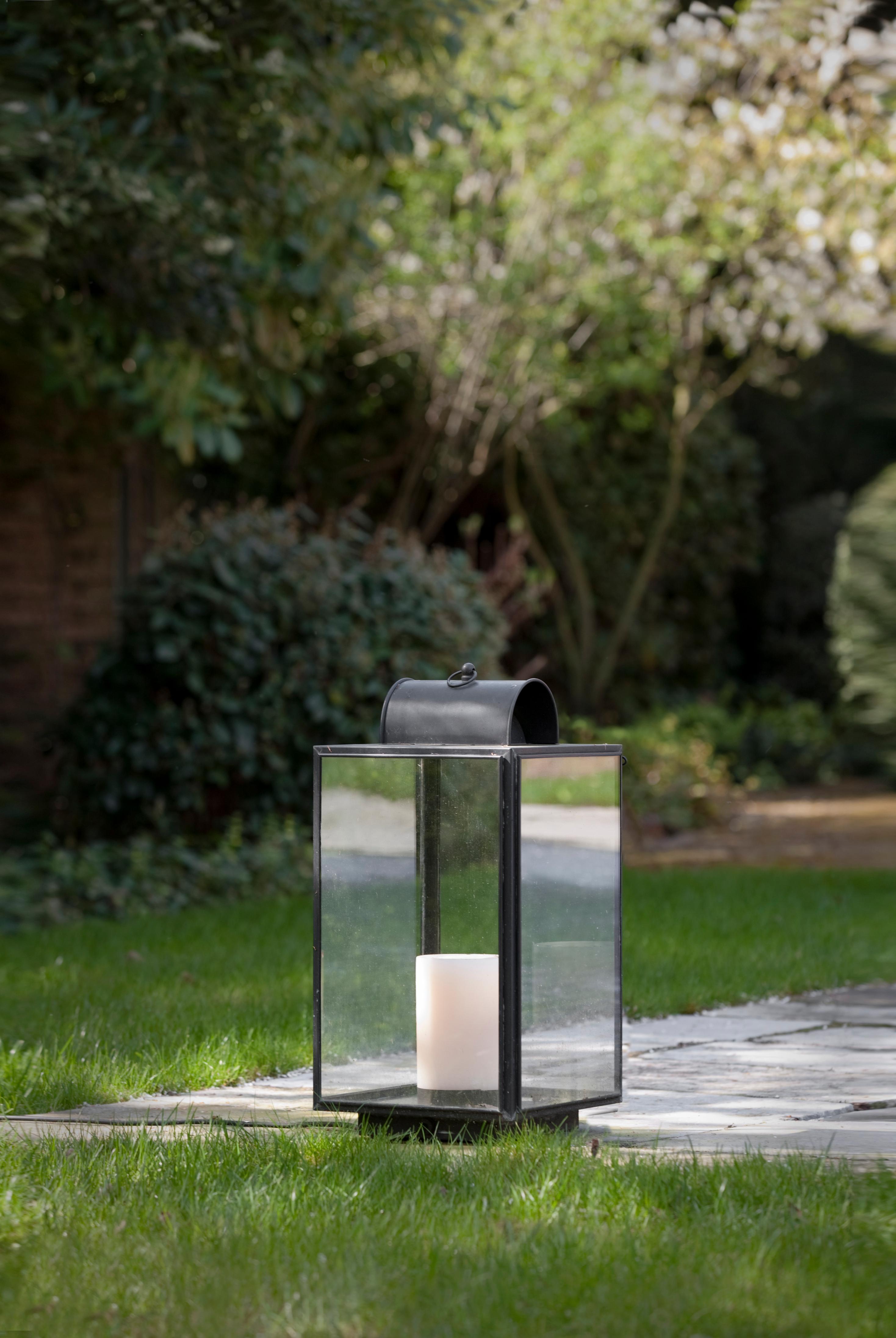 Candle light in dark bronze with outside fitted clear safety glass, ventilation through integrated superstructure with handle (eyelet), supplied with an oyster-white candle.

For indoor and outdoor use.