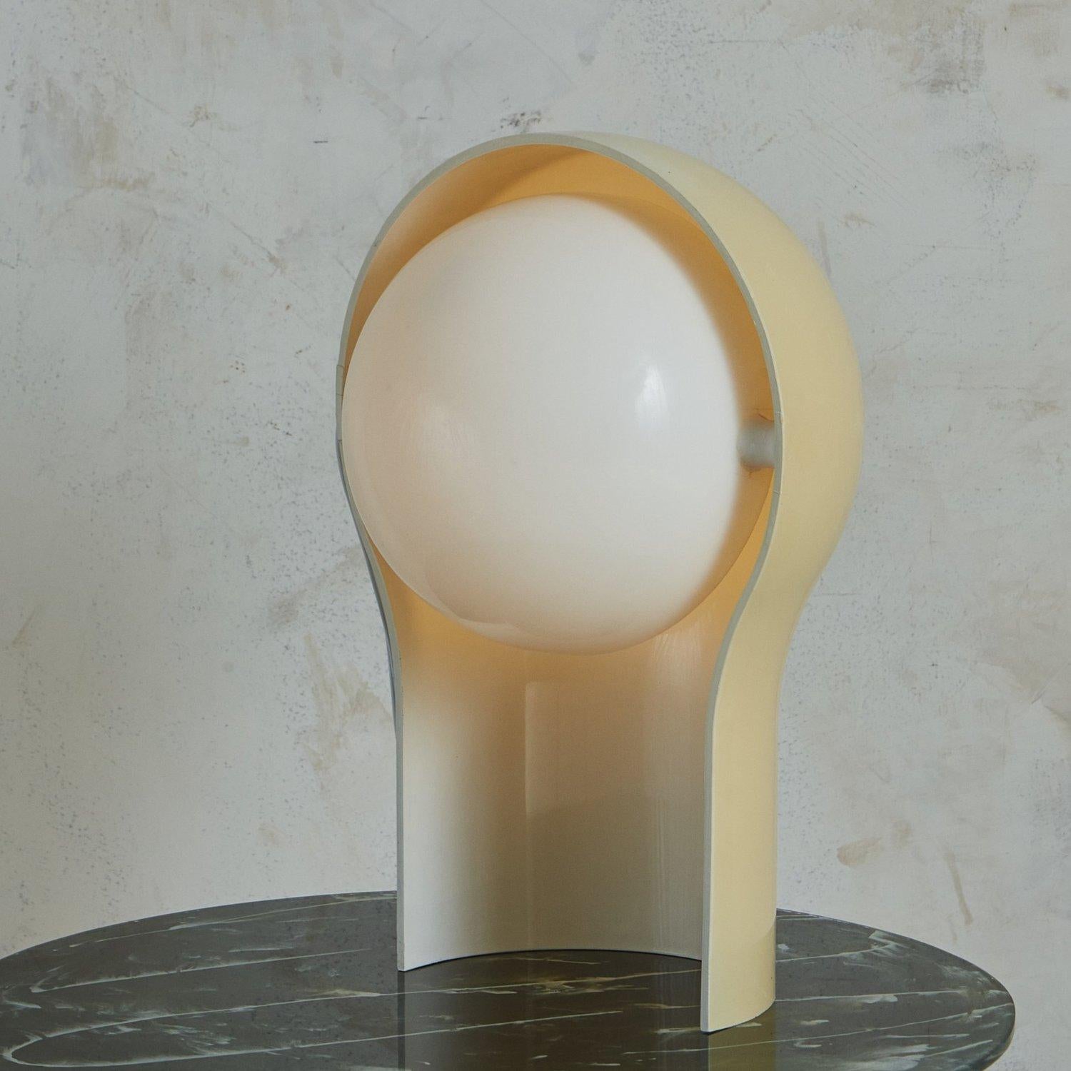A ‘Telegono’ table lamp designed by Vico Magistretti for Artemide in the 1960s. This sculptural lamp has a curved cream acrylic base with a rotating white acrylic demilune shade. When lit, it emits a warm glow. Unmarked. Sourced in Italy, 1960s.


