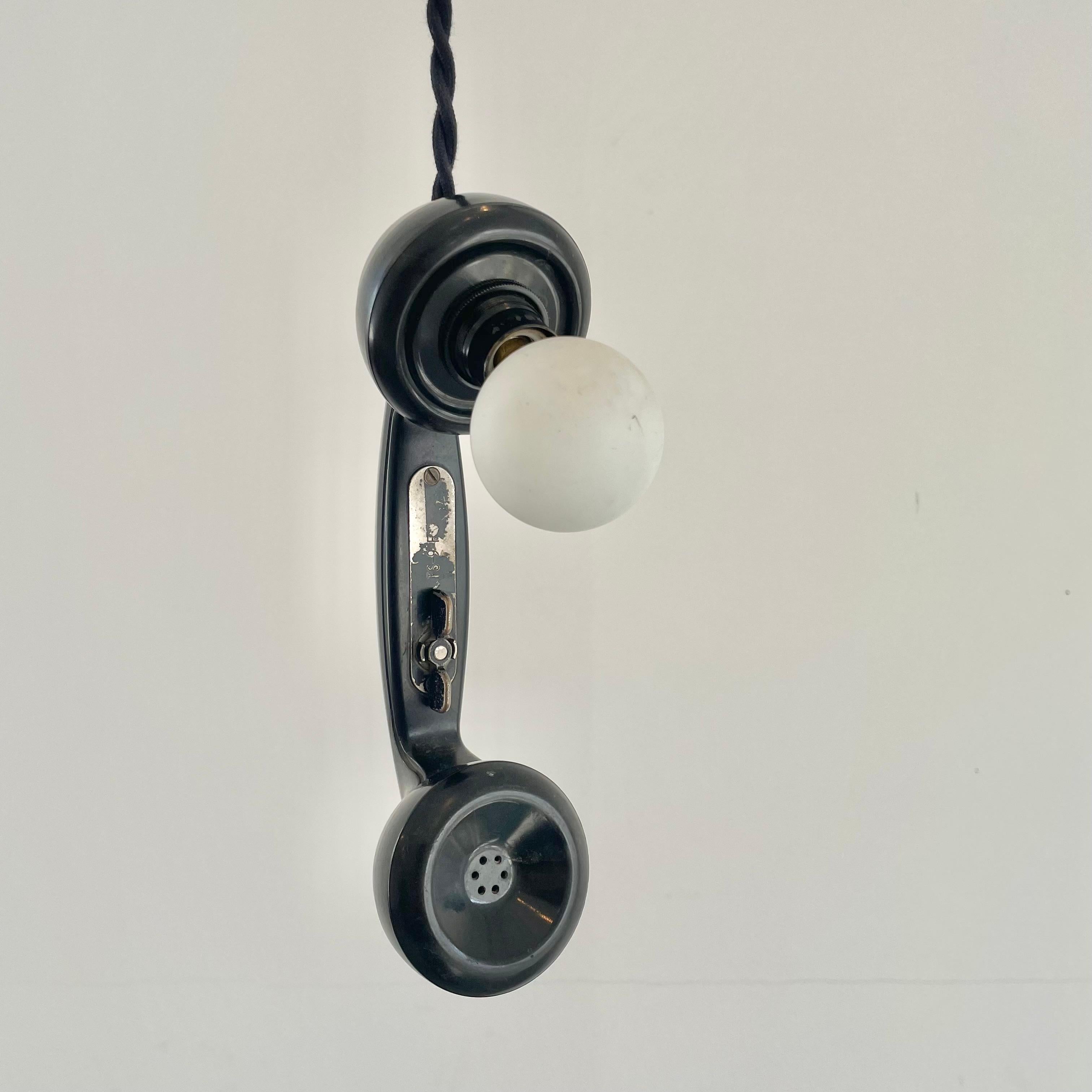 Lampe de téléphone incroyablement unique fabriquée à partir d'un vieux téléphone des années 60.  L'ampoule ambre éclaire magnifiquement et donne une impression de chaleur vintage. Elle peut être suspendue à un bar ou posée sur une table ou un
