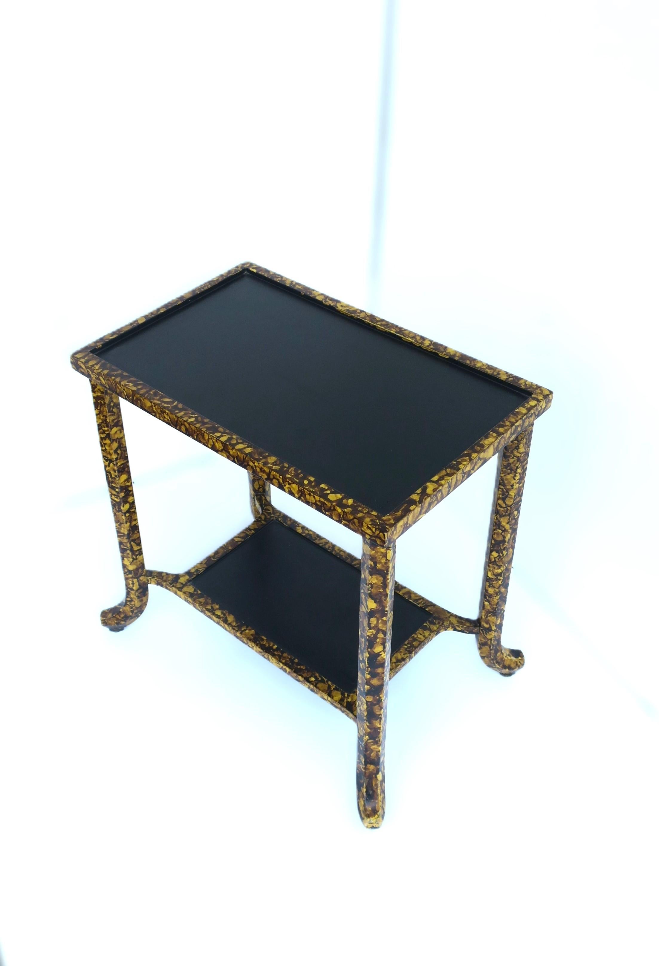 A telephone table/end table with lower shelf. Tables' top and shelf areas are black, edges and legs are black, brown and a golden yellow hue. A nice piece to support a cocktail or coffee/tea, etc., with a shelf area below for a book, etc. Table is