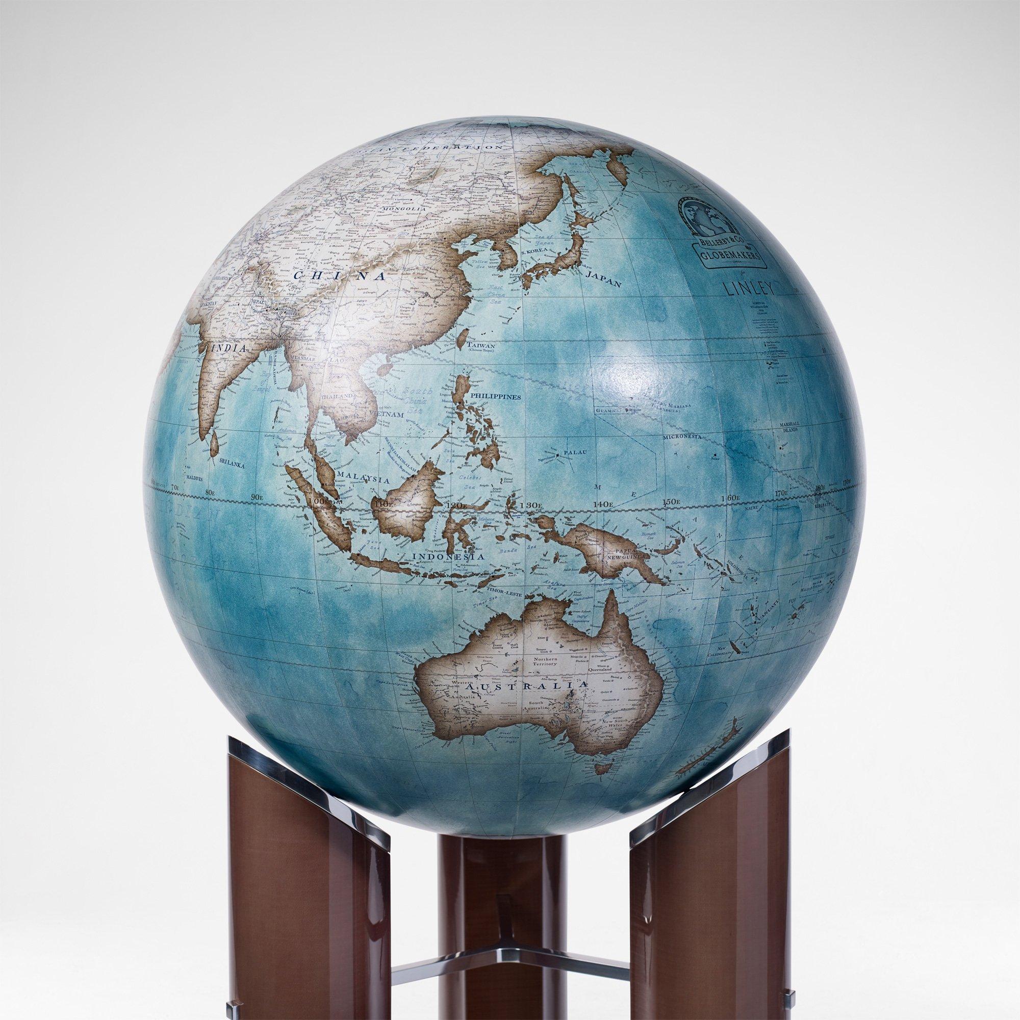 This striking piece features a 50cm diameter globe elevated on a sycamore dusk veneered stand with caps, brace detailing and a highly polished base in aluminium brass. The globe rests on three roller bearings, which allow for a fluid and unimpeded