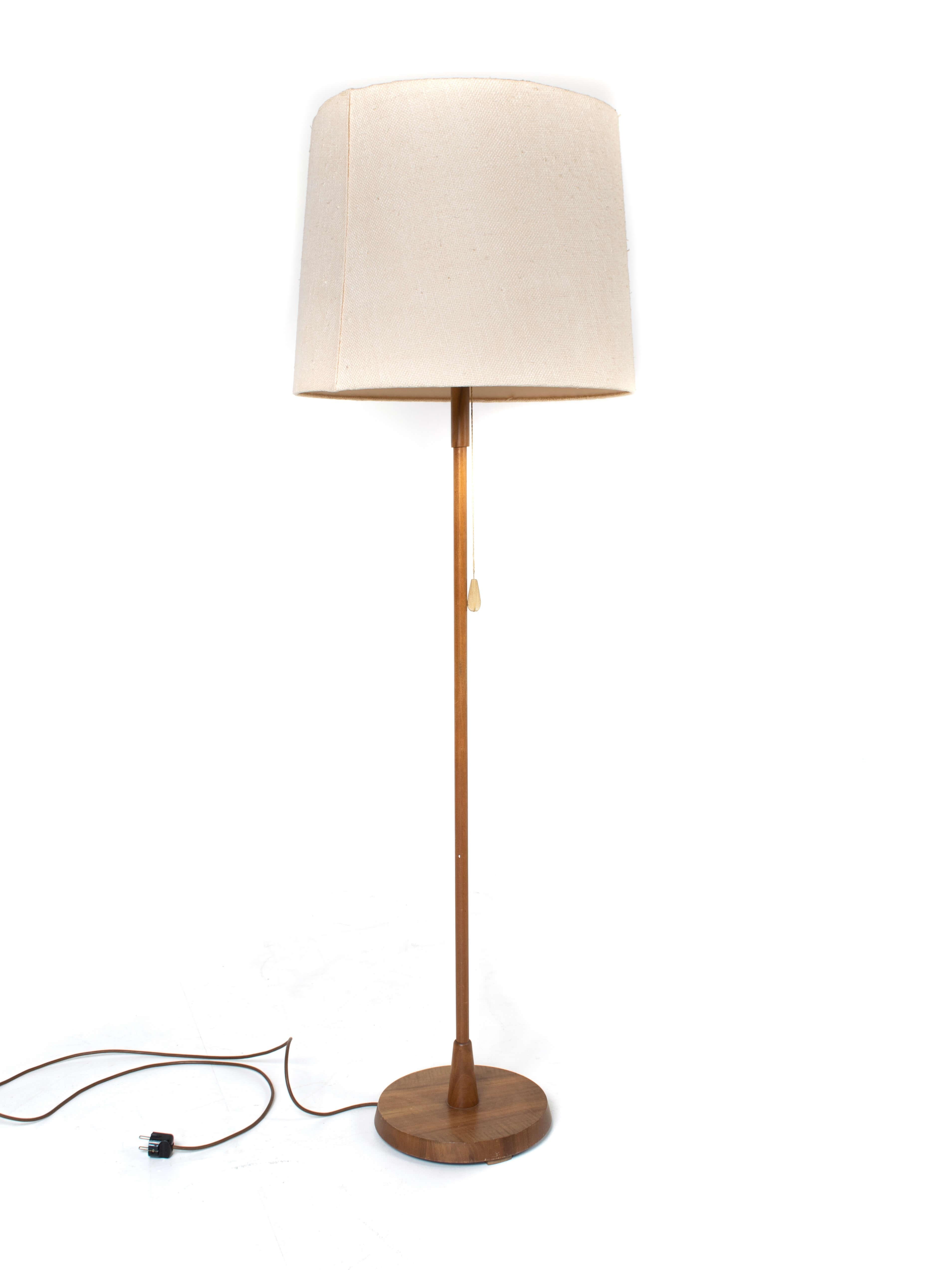 Temde floor lamp in teak and fabric from Germany, 1970s. This lamp has a teak base and a fabric hood with rice paper on top. The lamp can be adjusted in two heights with a metal mechanism. On top the rice paper sheet has some wear and tear due to