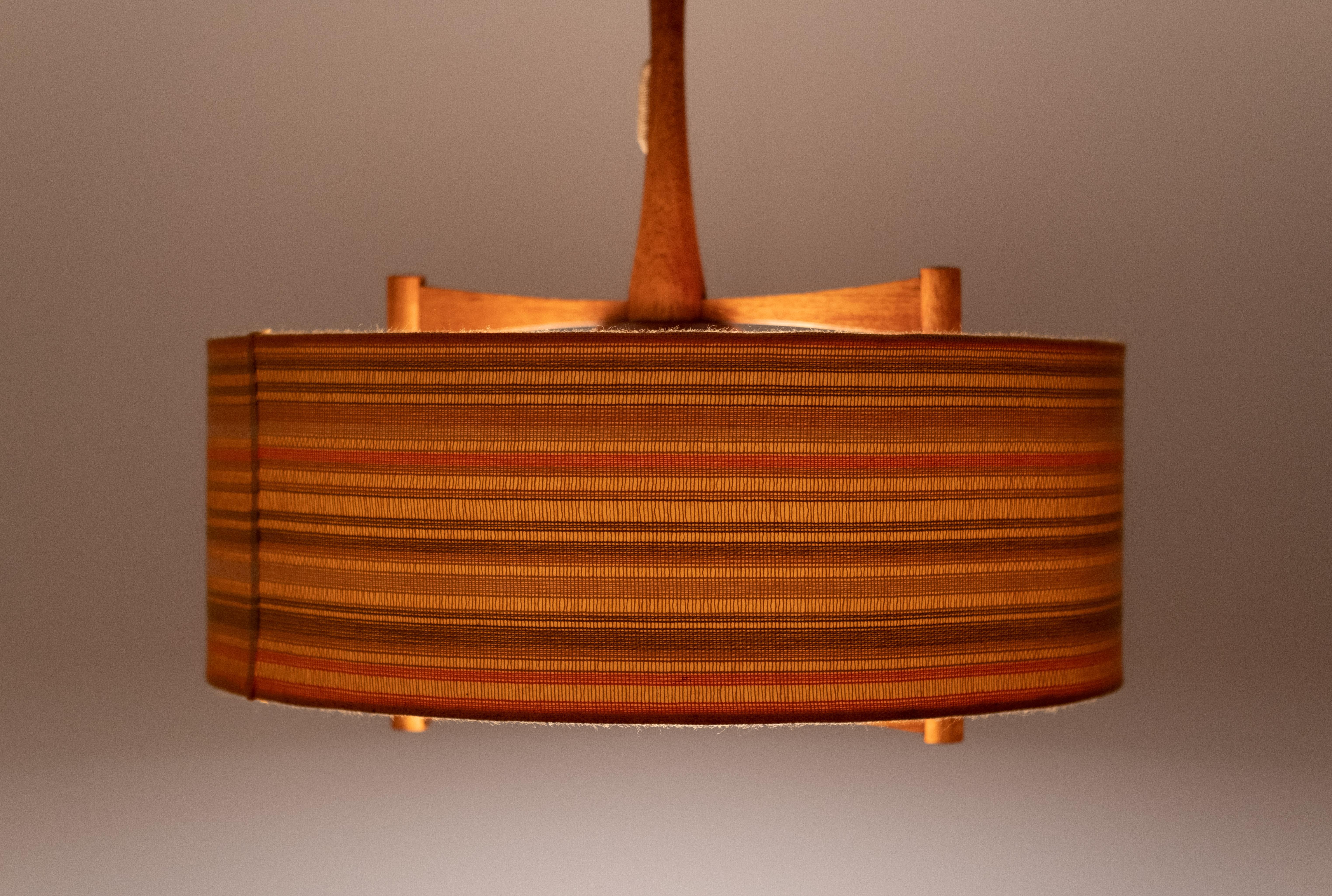 Fantastic pendant lamp by Temde Germany 1960s. Teak frame. milk glass inner shade,
comes with the original fabric shade. In orange and brown typical for that era. In a very good condition.
   