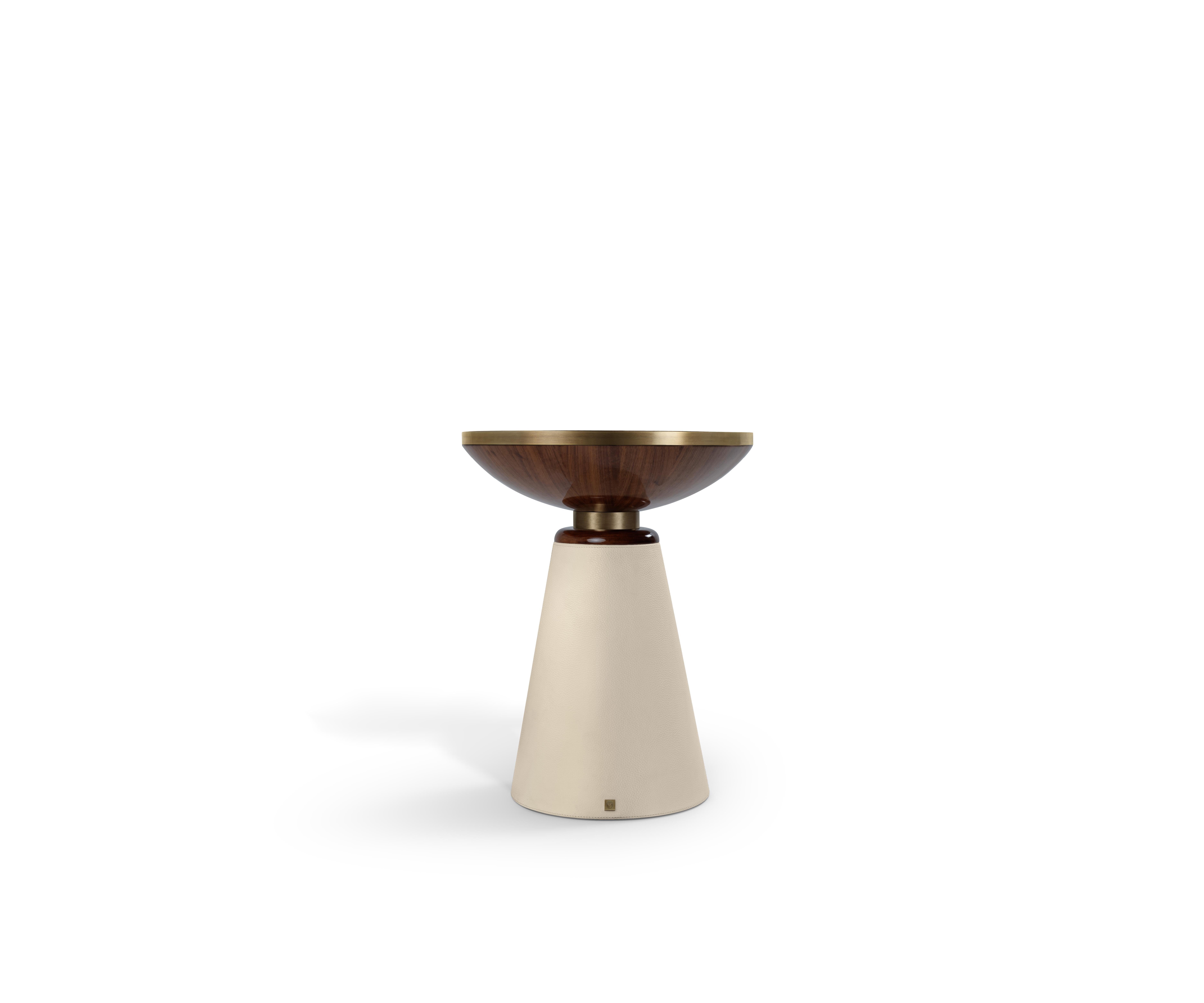 A refined interplay of tone, texture, and form.

The tabletop features a radial walnut veneer finished in high gloss and framed with a deep brass rim, adding a touch of quiet opulence.
Its base, conical in form, is wrapped in neutral leather for a