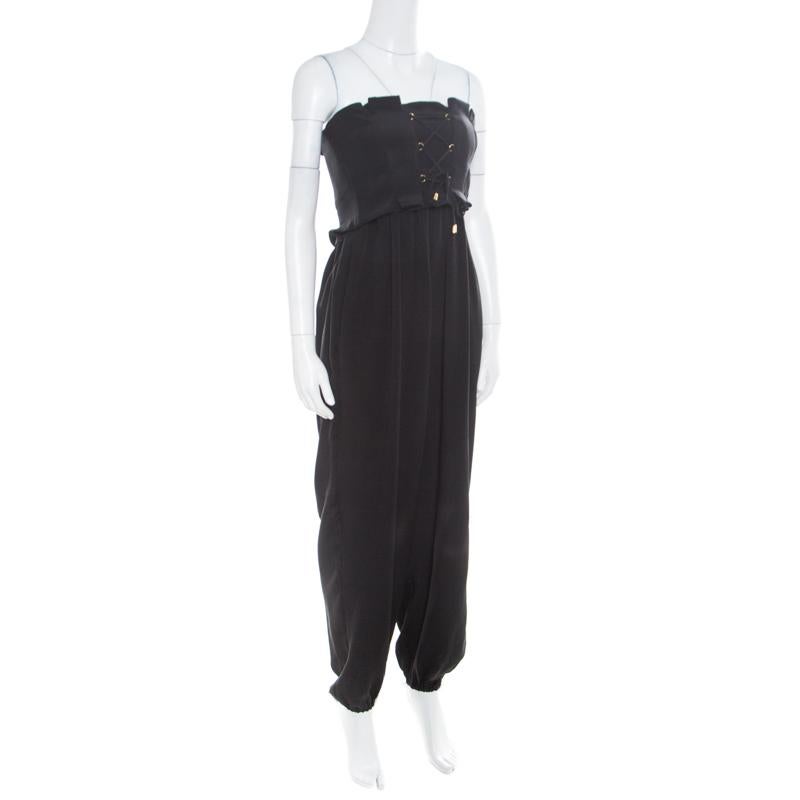 This strapless harem jumpsuit from Temperley London is a fine blend of effortless style and power dressing! This black creation is made of 100% silk and features a pleated silhouette. It flaunts a criss-cross self-tie detailing on the bustier and