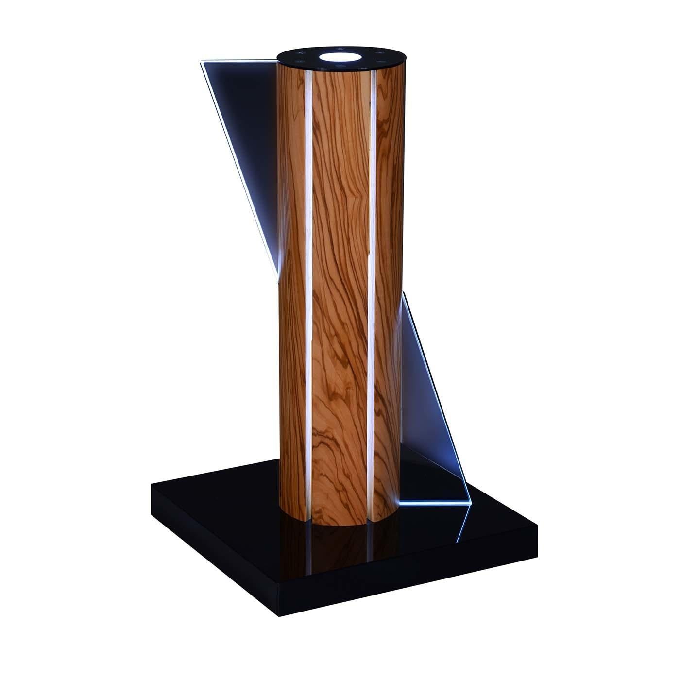 This olive wood table lamp represents the durability of olive trees as they grow over the centuries. When struck by lightning on a stormy night, however, nature will leave its mark on some of them with a bright light piercing their trunk. White LED