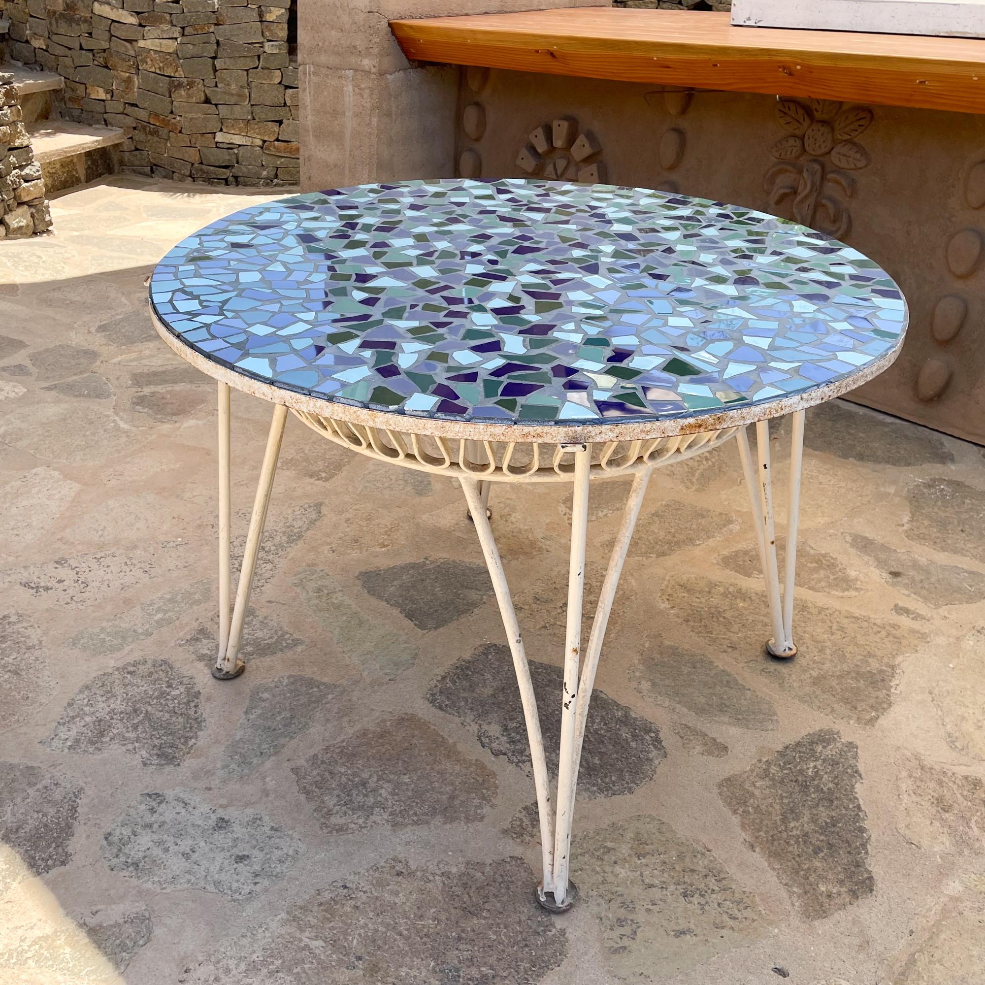 Maurizio Tempestini for Salterini round patio dining table wrought iron ribbon antique white with blue mosaic tile top.
Cute Scallop Curly Q Ribbon Swirl detail on wrought iron base. Beautiful blue sea Mosaic tile top.
Measures: 29.25t x 42