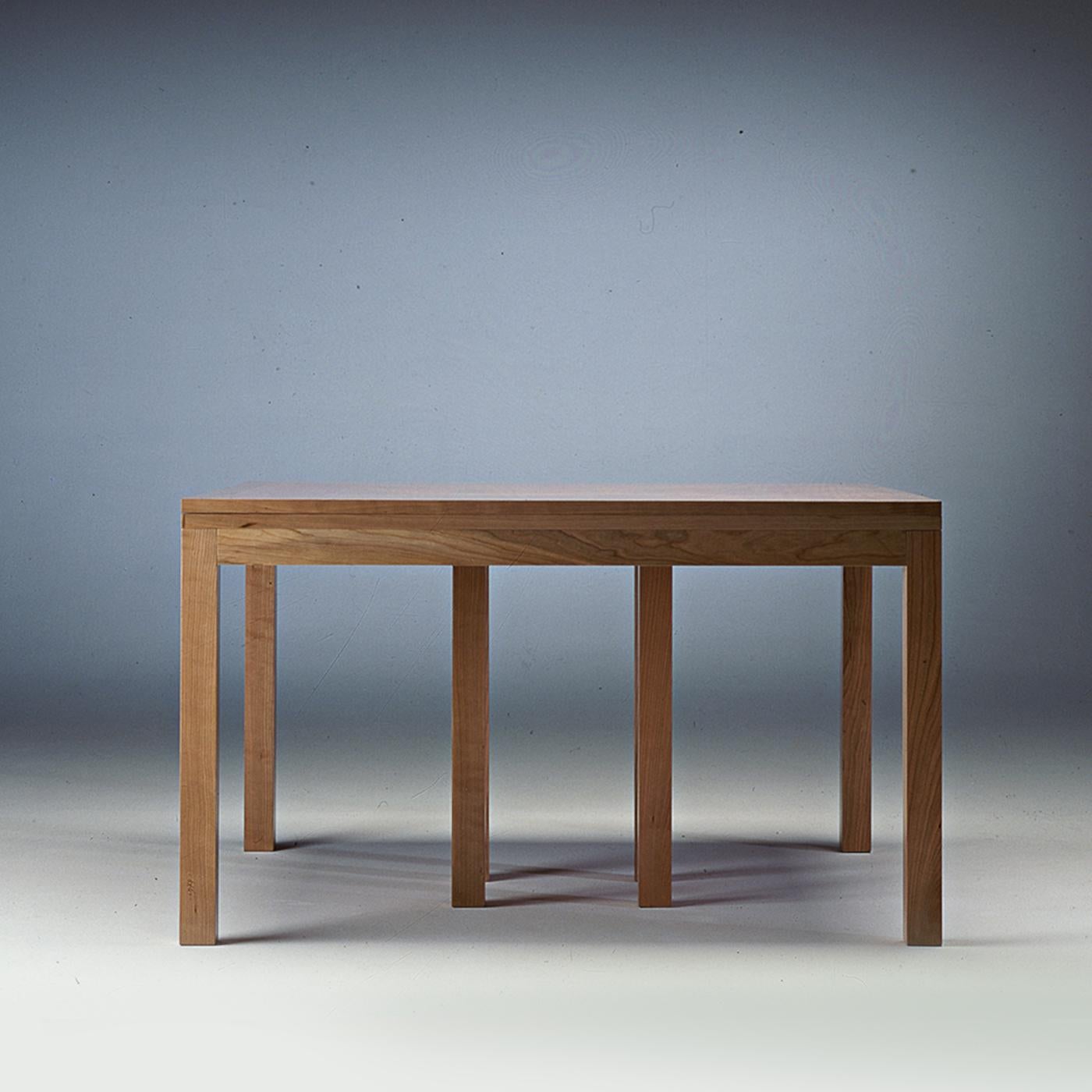 This elegant extendible table has a square top that features cherrywood with delicate inlays in pear wood. It can also be made in walnut wood with inlays in maple wood. If the preference is for the consistent look given by one type of wood only, it