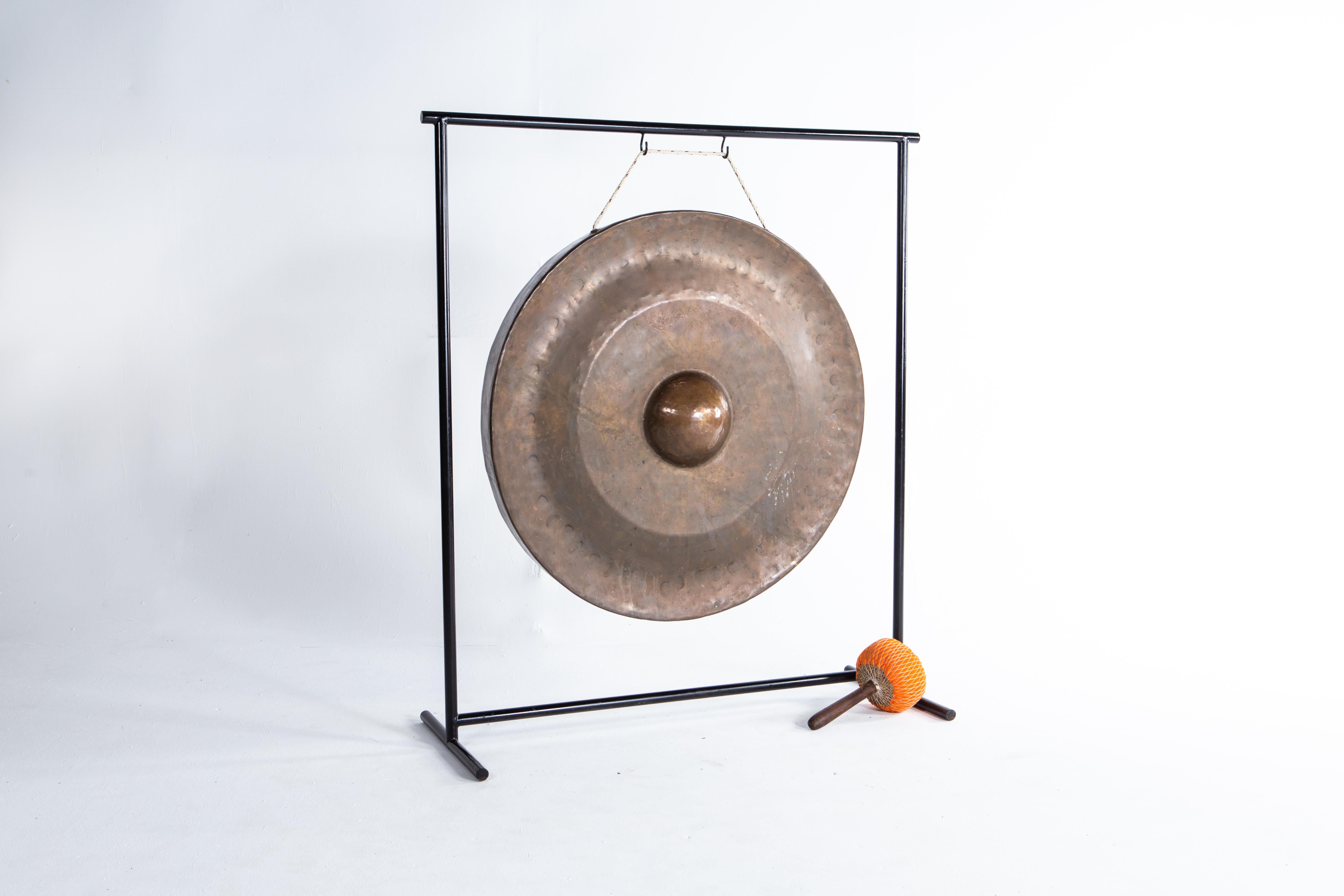 Large bronze gongs are suspended adjacent to Thai temple to allow visitors to make merit by sounding them.   This gong was once given to a temple in the Chiang Mai area to gain merit for the giver. According to Buddhist belief, meritorious gifts