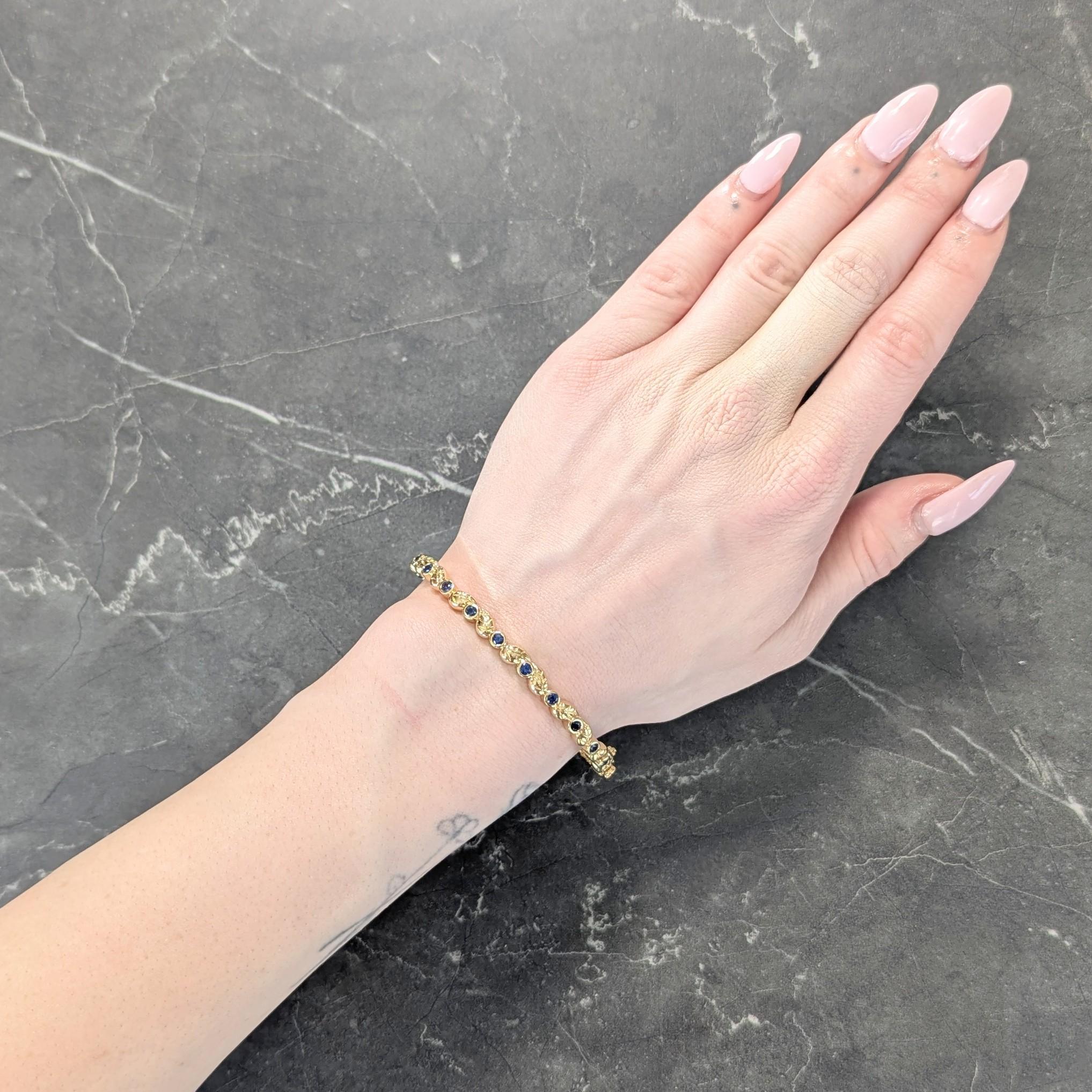 Bangle is comprised of gold foliate forms with engraved leaf details
Featuring round cut sapphires bezel set in pattern fully around
Weighing approximately 1.75 carats total
Transparent medium blue in color
Opens on a hinge via press release clasp