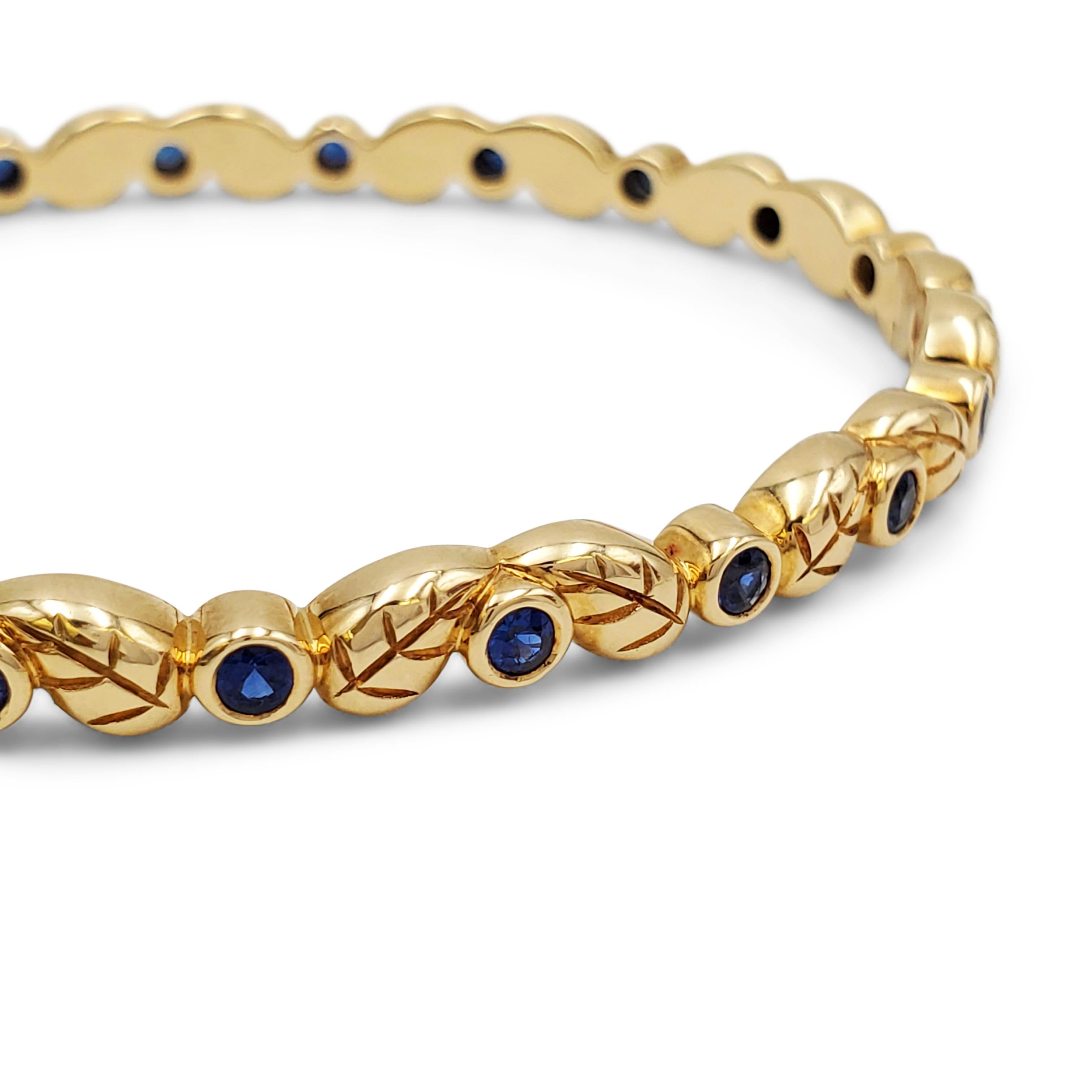 Authentic Temple St. Clair bracelet crafted in 18 karat gold.  A pattern of carved leaves is accented by lively bezel-set sapphires of an estimated 1 carat total weight. The bracelet has a 6 3/4 inch internal circumference and measures 5mm in width.