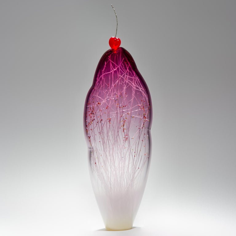 Temptation I, is a hand-blown glass sculpture by the collaborative artists Hanne Enemark (Danish) and Louis Thompson (British) Incorporating an outer form in clear and pink glass which contains a multitude of white glass canes and candy-colored,