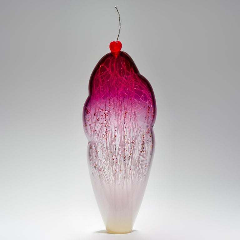 Temptation III, is a hand-blown glass sculpture by the collaborative artists Hanne Enemark (Danish) and Louis Thompson (British) Incorporating an outer form in clear and pink glass which contains a multitude of white glass canes and candy-colored,
