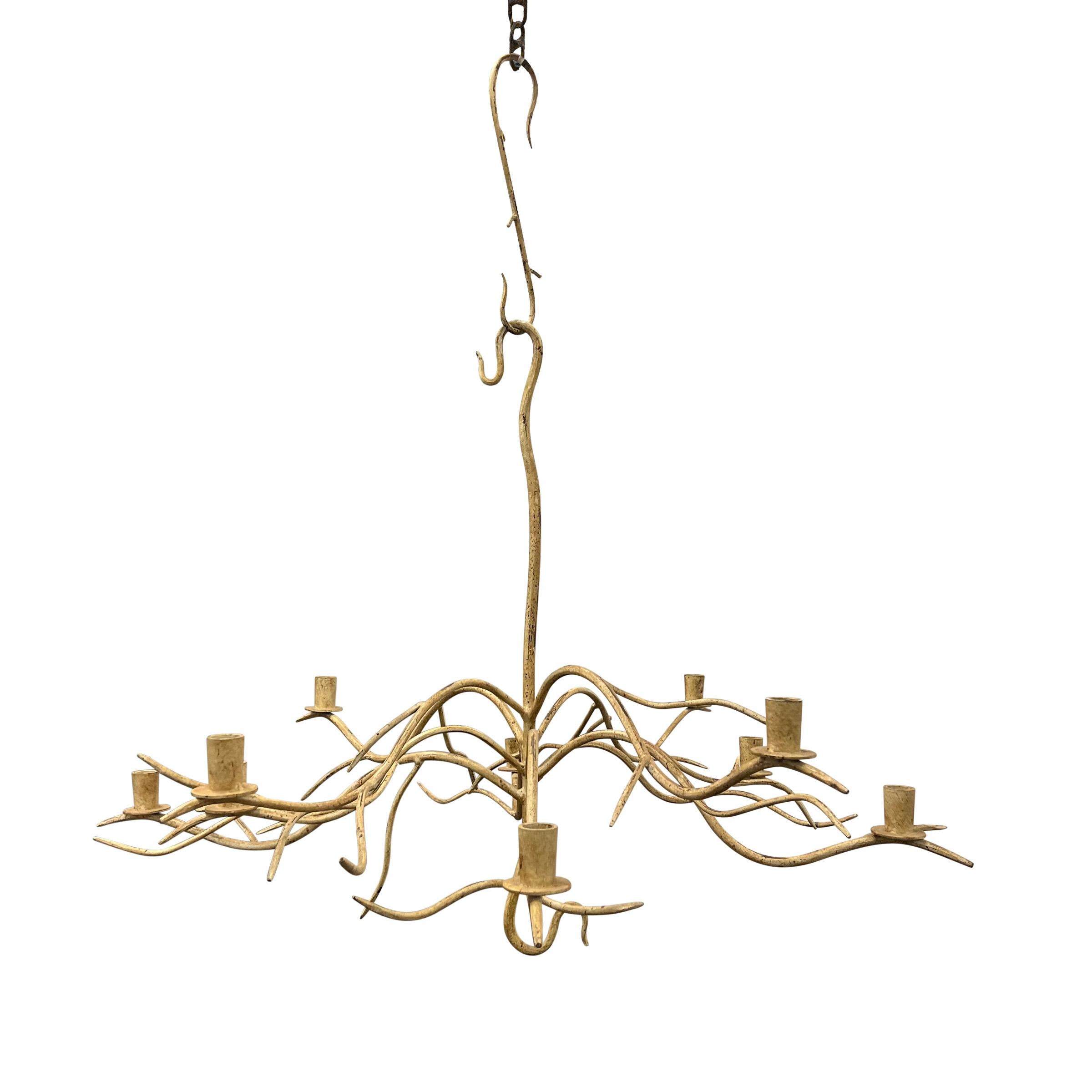 Eleva il tuo spazio con una miscela armoniosa di tradizione e stile contemporaneo grazie a questo squisito lampadario a bracci in ferro battuto a mano. Con dieci bracci che scorrono con grazia, ognuno dei quali è ornato da un portacandela, emana un