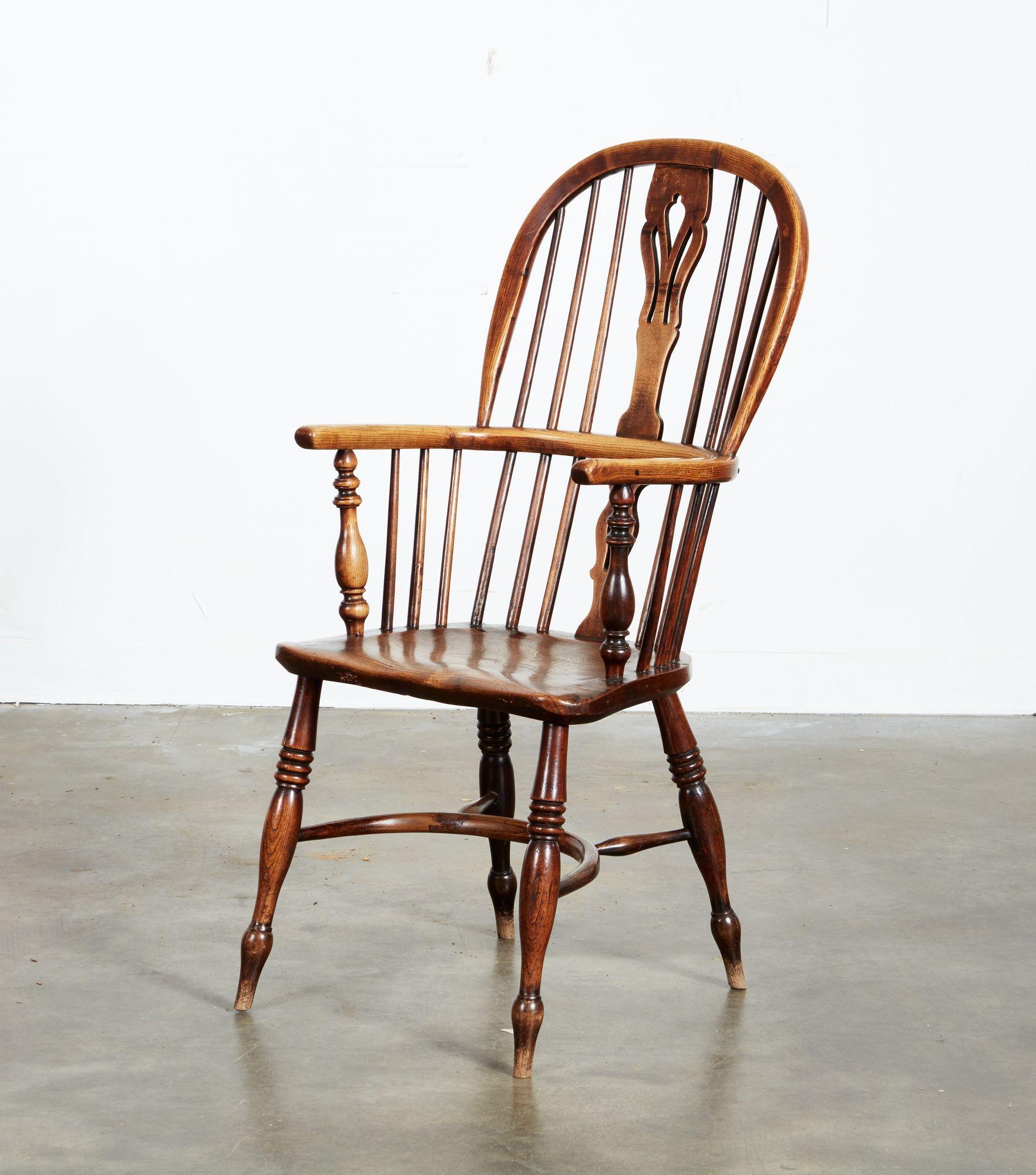 Ten English ash and elm high back Windsor armchairs having tulip pierced fruitwood backsplats, bent hoop backs and continuous arms, each dished seat fashioned from a single elm plank, standing on boldly turned legs and joined by crinoline