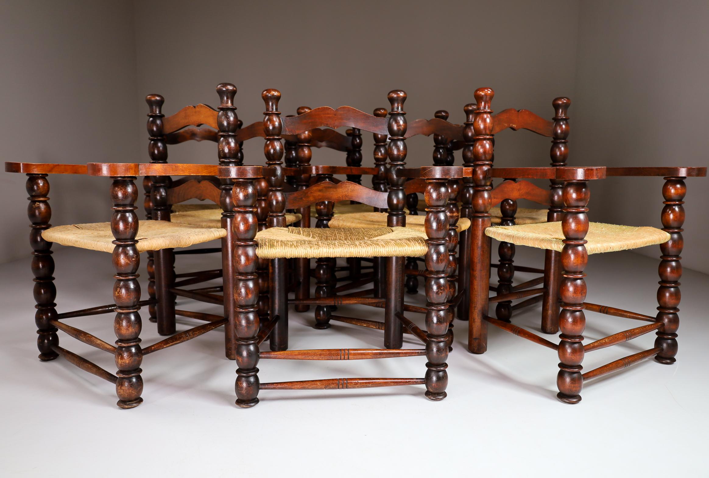 Rare set of ten French dining armchairs in the style of Charles Dudouyt. Gorgeous patina'd wood frames with signature sculptural ball shapes. Woven rushed seats. Unique set of ten chairs.
    