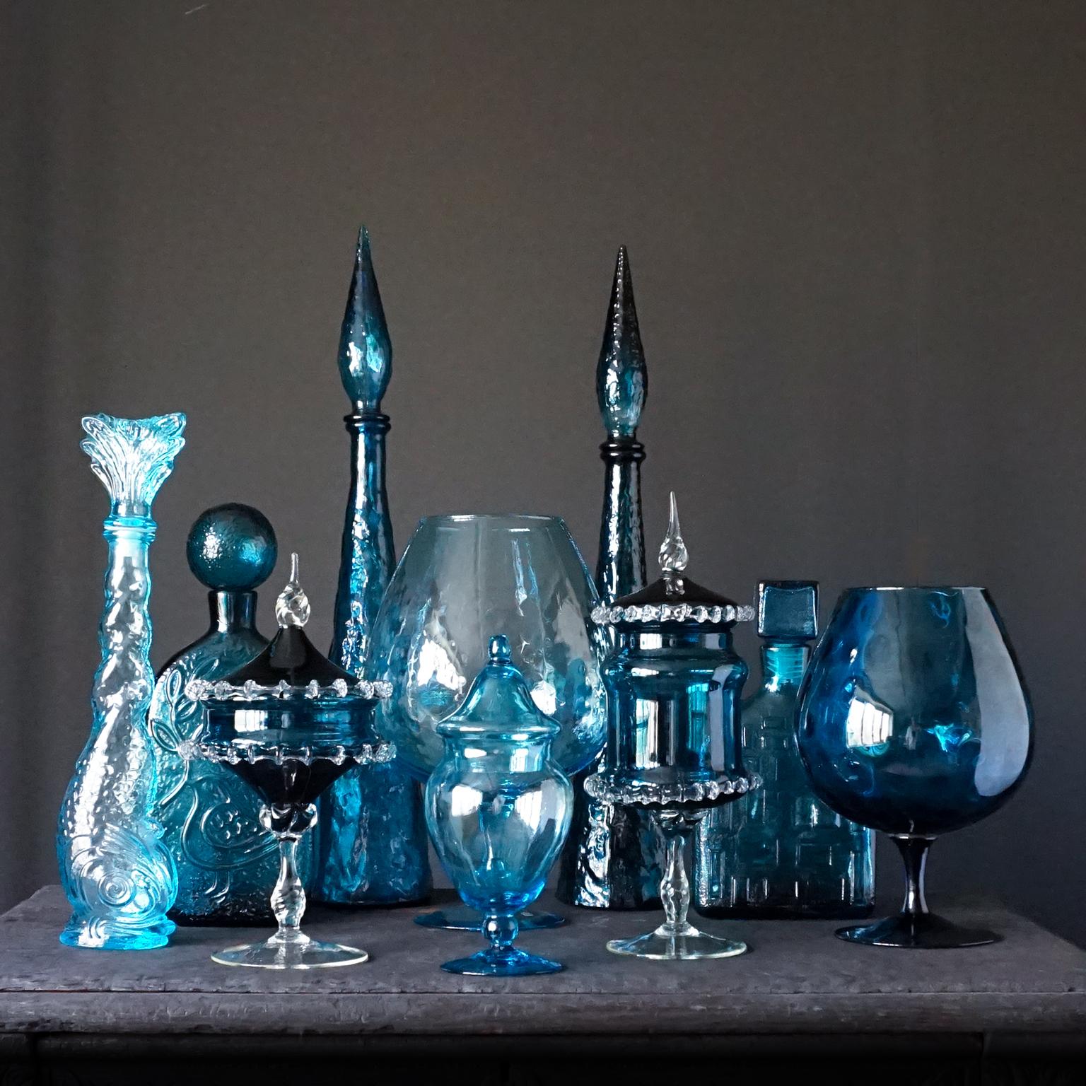 Very decorative blue set of ten different size Italian blown and pressed glass bottles.
Two pressed genie bottles, a pressed bird design carafe, a pressed square carafe, a pressed fish carafe, two blown cognac glasses as vase and three apothecary