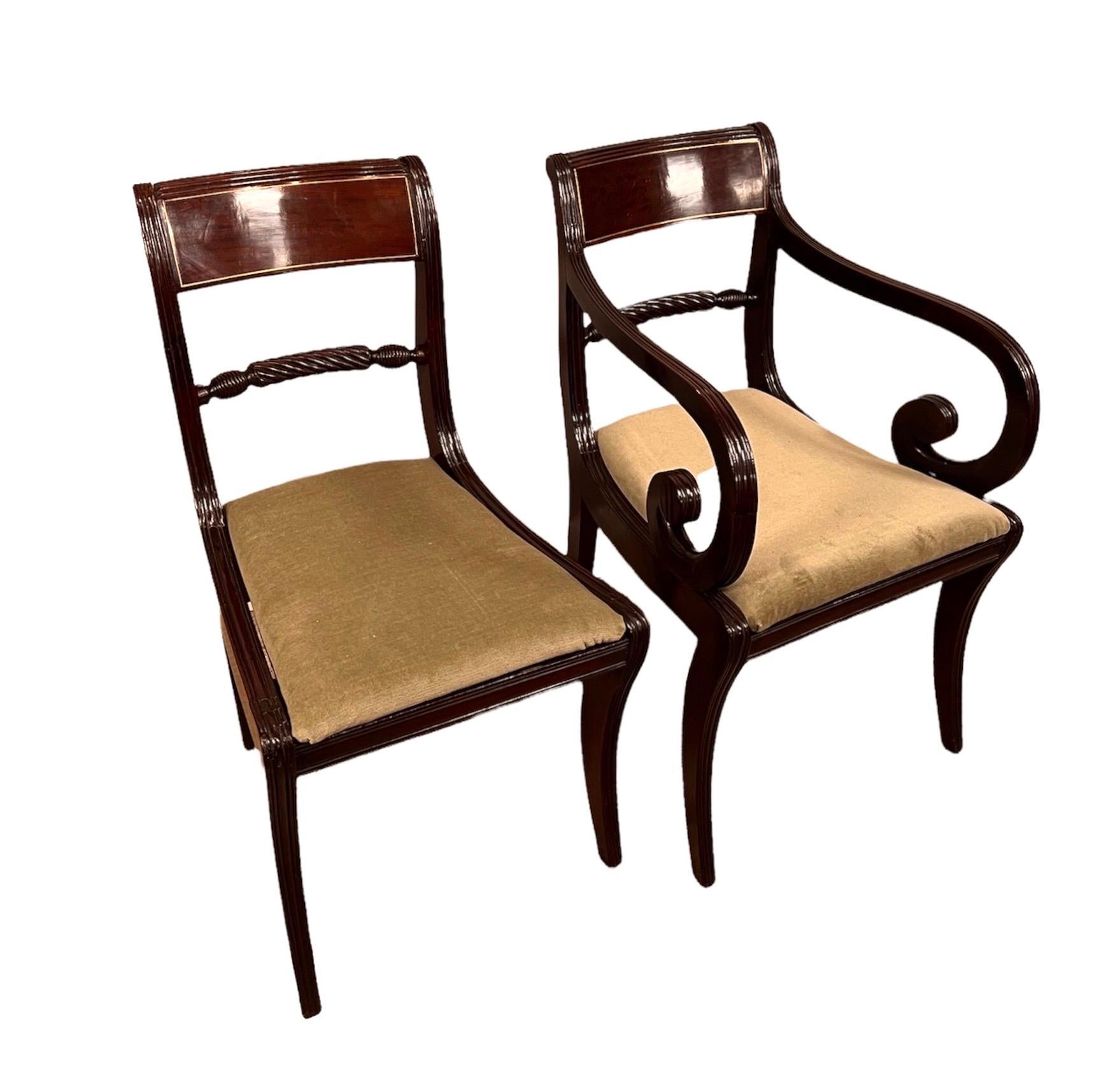 A set of ten Regency mahogany dining chairs, c.1810 2 Arm , 8 Side chairs the panelled crest rails with Brass line inlay , above turned rope twist splats, over upholstered slip seats, raised on sabre legs (10) total.