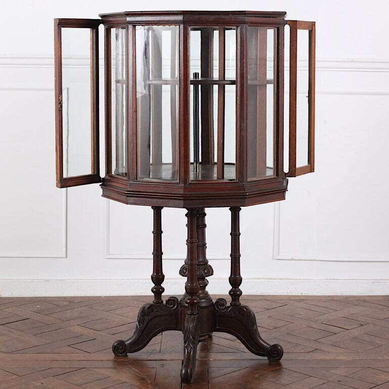 Unusual late Victorian English mahogany ten sided vitrine with two opening glass doors on opposite sides of the case, and raised up on turned column legs with carved scrolled lower feet. The interior is fitted with a revolving two-level ‘lazy Susan’