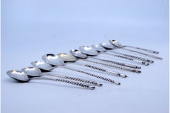 Ten silver dessert spoons with engraved shells and twisted Russian handles