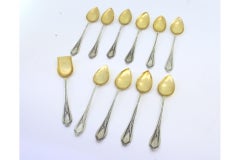 Ten silver teaspoons and sugar shovel with gilt shell and handle reliefs