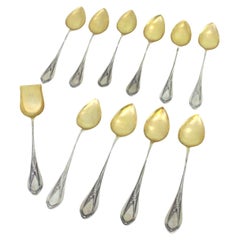 Ten silver teaspoons and sugar shovel with gilt shell and handle reliefs