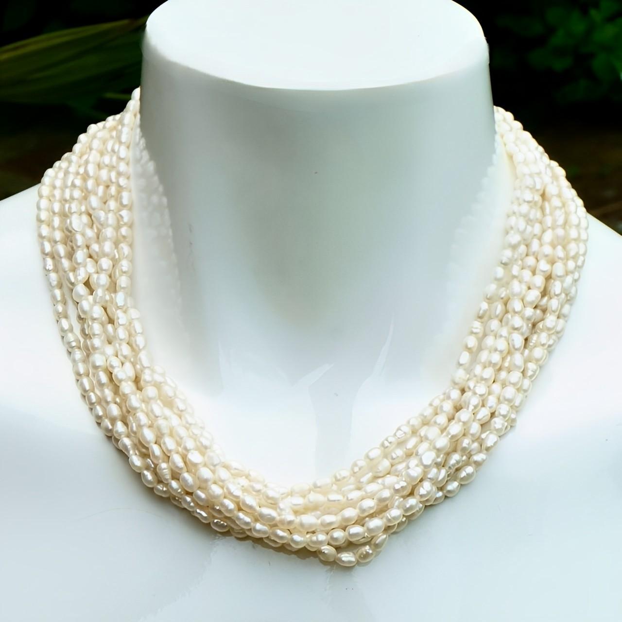 Dix rangs de perles de riz baroques avec un fermoir plaqué or et fausses perles. Le collier mesure 46 cm de long. Les perles ont une belle couleur ivoire et un lustre subtil. Le collier est en très bon état, avec une usure du placage d'or sur le