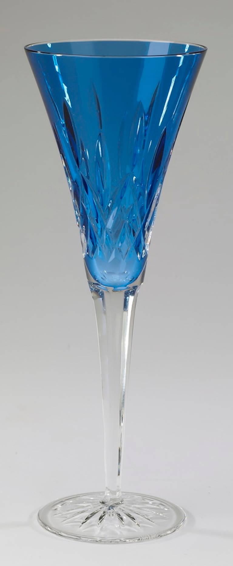Set of ten Waterford sapphire crystal fluted champagne glasses in the 'Lismore' pattern, each having a fluted sapphire bowl with a cut geometric motif, rising on a faceted tapering stem, and terminating in a round foot, with acid etched Waterford