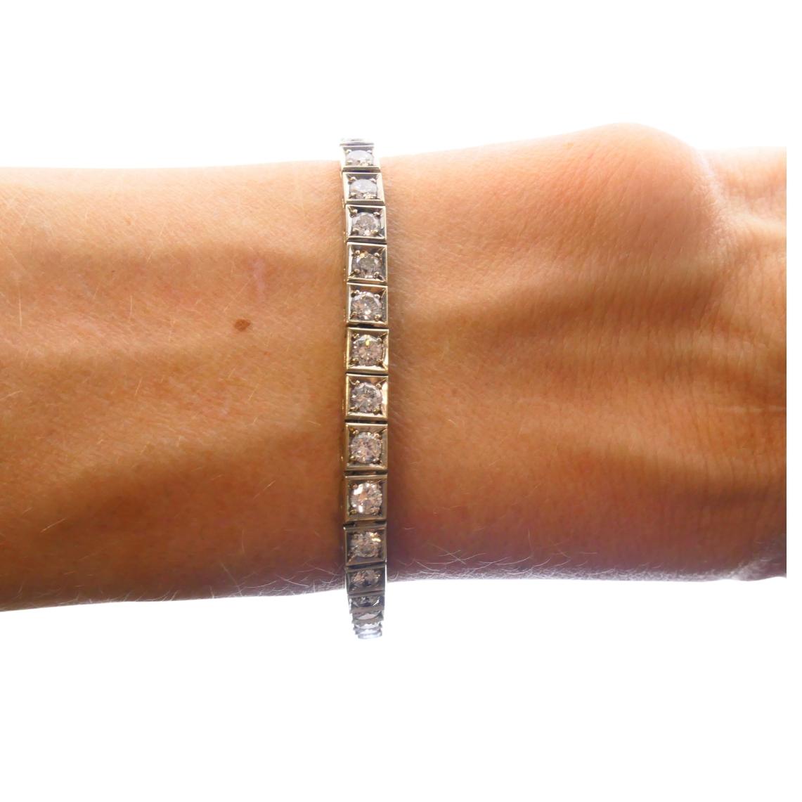 Esta pulsera tenis de oro de 18 quilates presenta una línea limpia y estructurada de 40 diamantes de talla cuadrada, engastados en canal en una fila continua. Los diamantes tienen un peso combinado aproximado de 4 quilates. Mide 7 pulgadas de largo