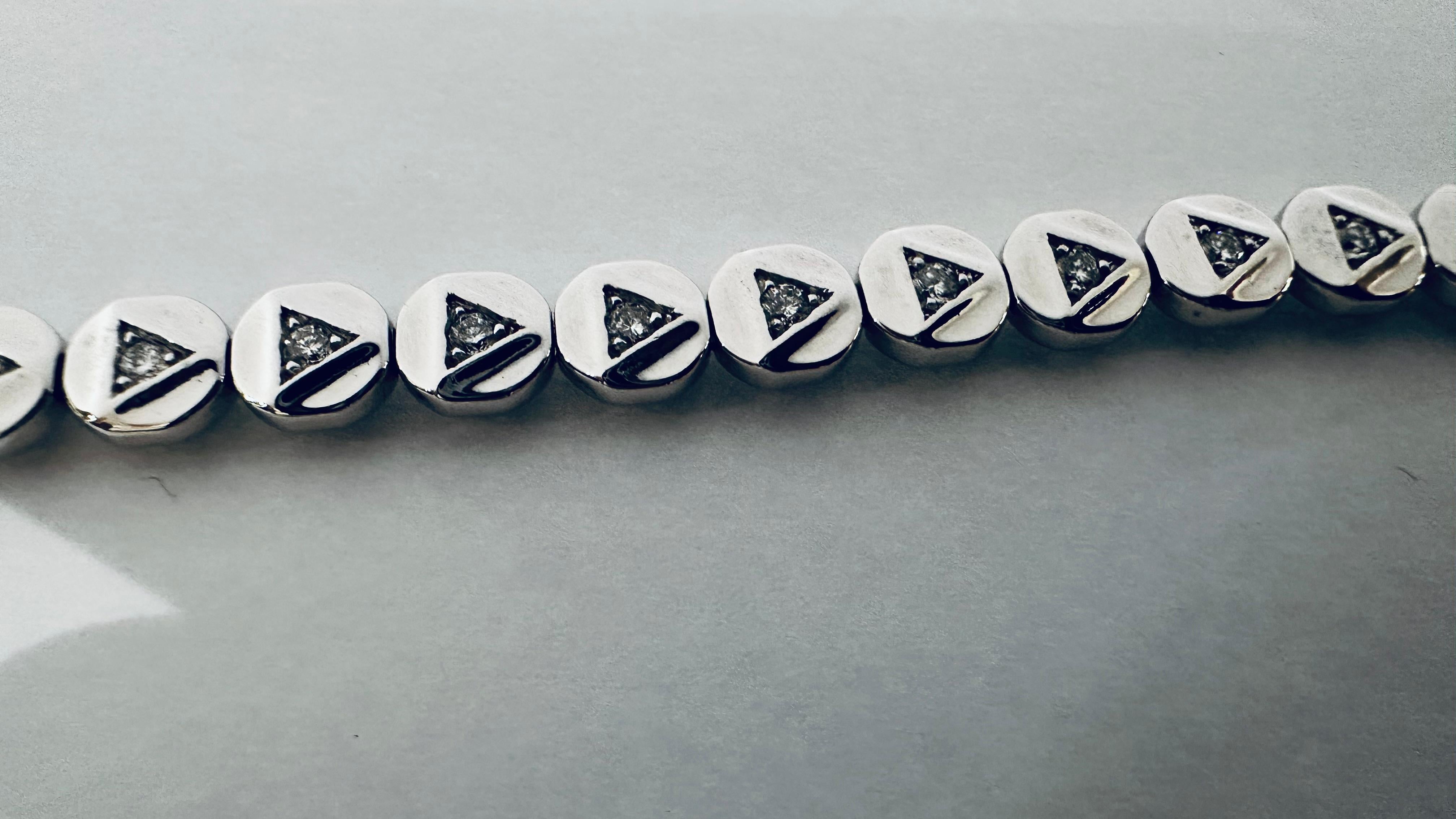 Cet extraordinaire tennis en or blanc 18 carats est un bijou exclusif, orné de diamants totalisant 1,47 carats, de couleur F et de pureté VS. La particularité du design réside dans les diamants sertis en forme triangulaire, qui confèrent au bracelet